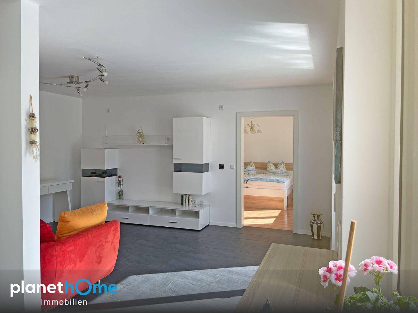 Heller Wohnbereich mit moderner Einrichtung und offenem Zugang zu einem Schlafzimmer.