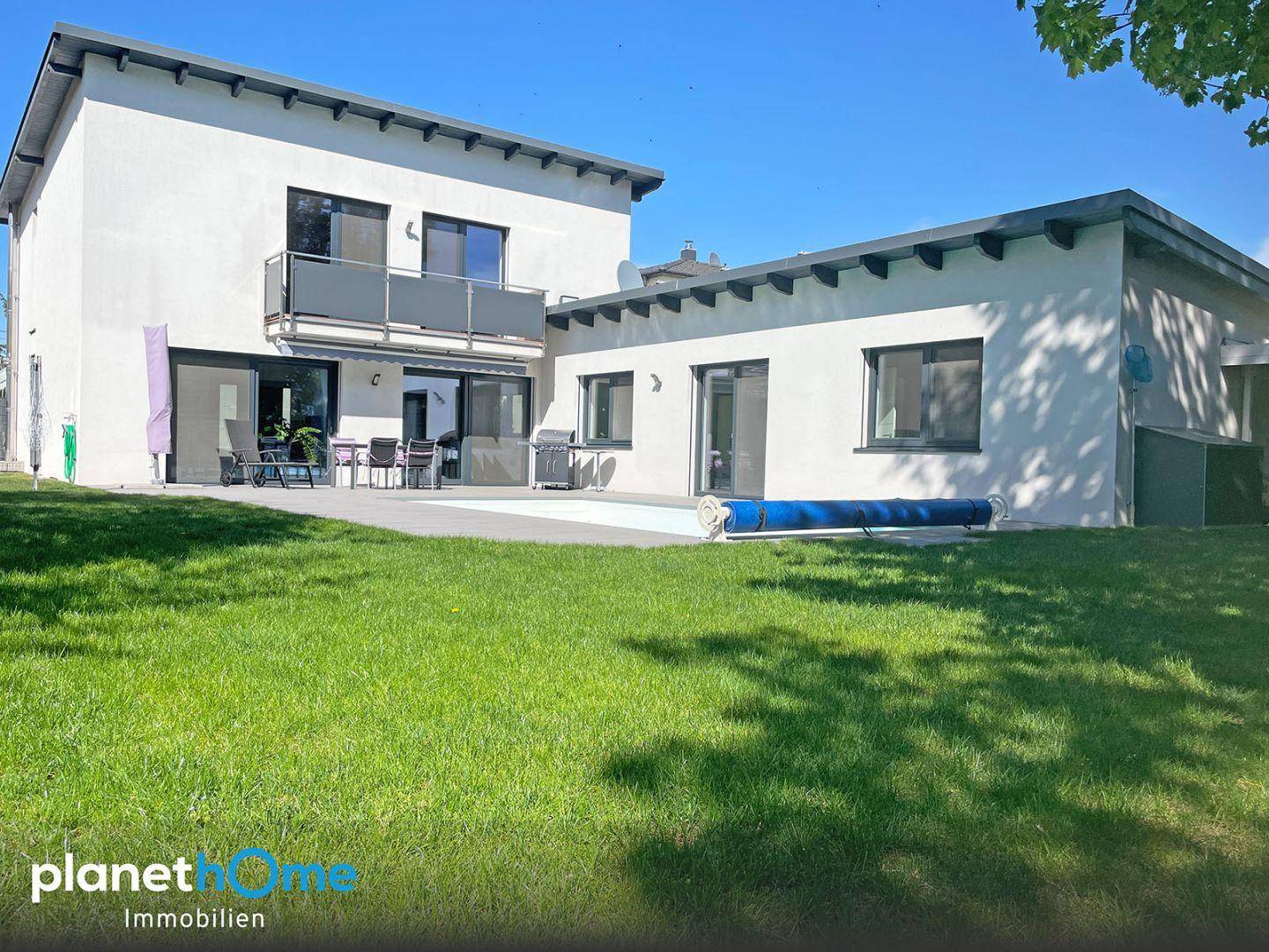 Gesamtaufnahme des modernen Hauses mit großem Garten, Pool und Terrasse.