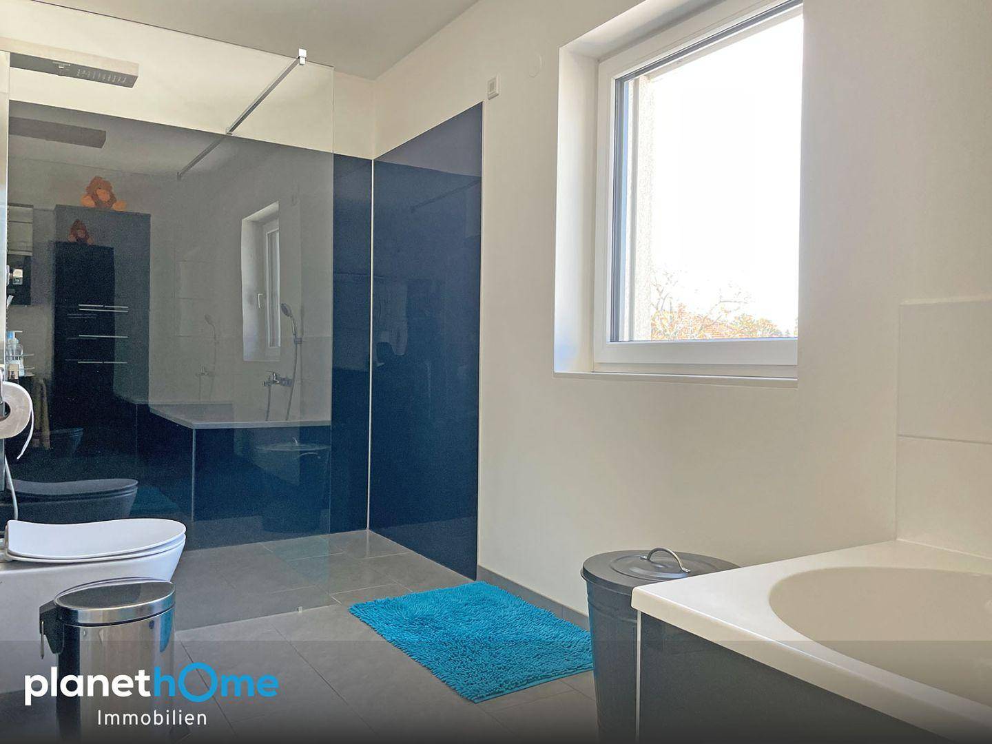 Modernes Badezimmer mit großer Dusche, Fenster und dunklen Akzenten.