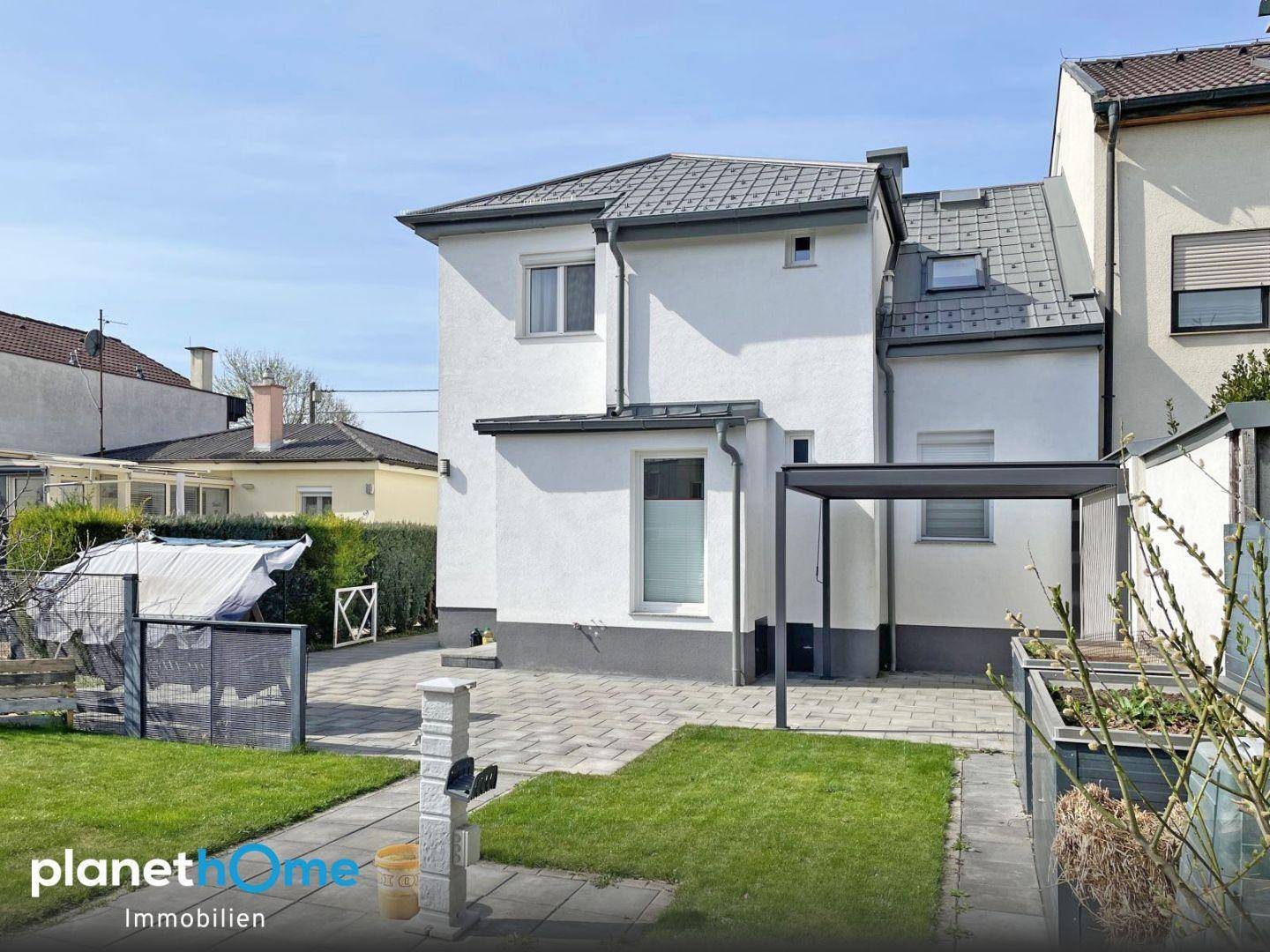 Rückansicht des Hauses mit Gartenbereich, Rasen und einem gepflasterten Weg.