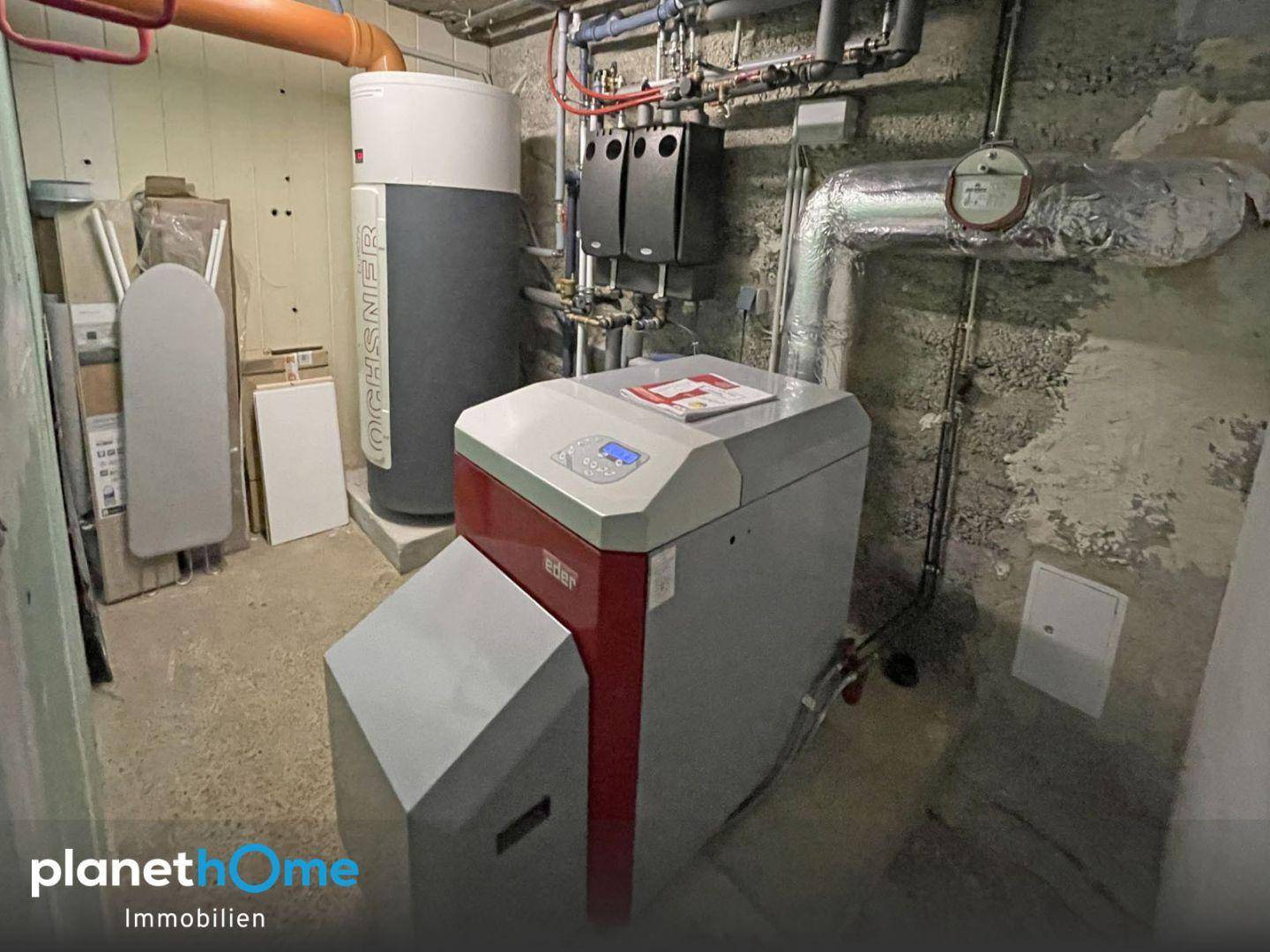 Technikraum im Keller mit moderner Heizungsanlage, Warmwasserspeicher und sichtbaren Rohren.