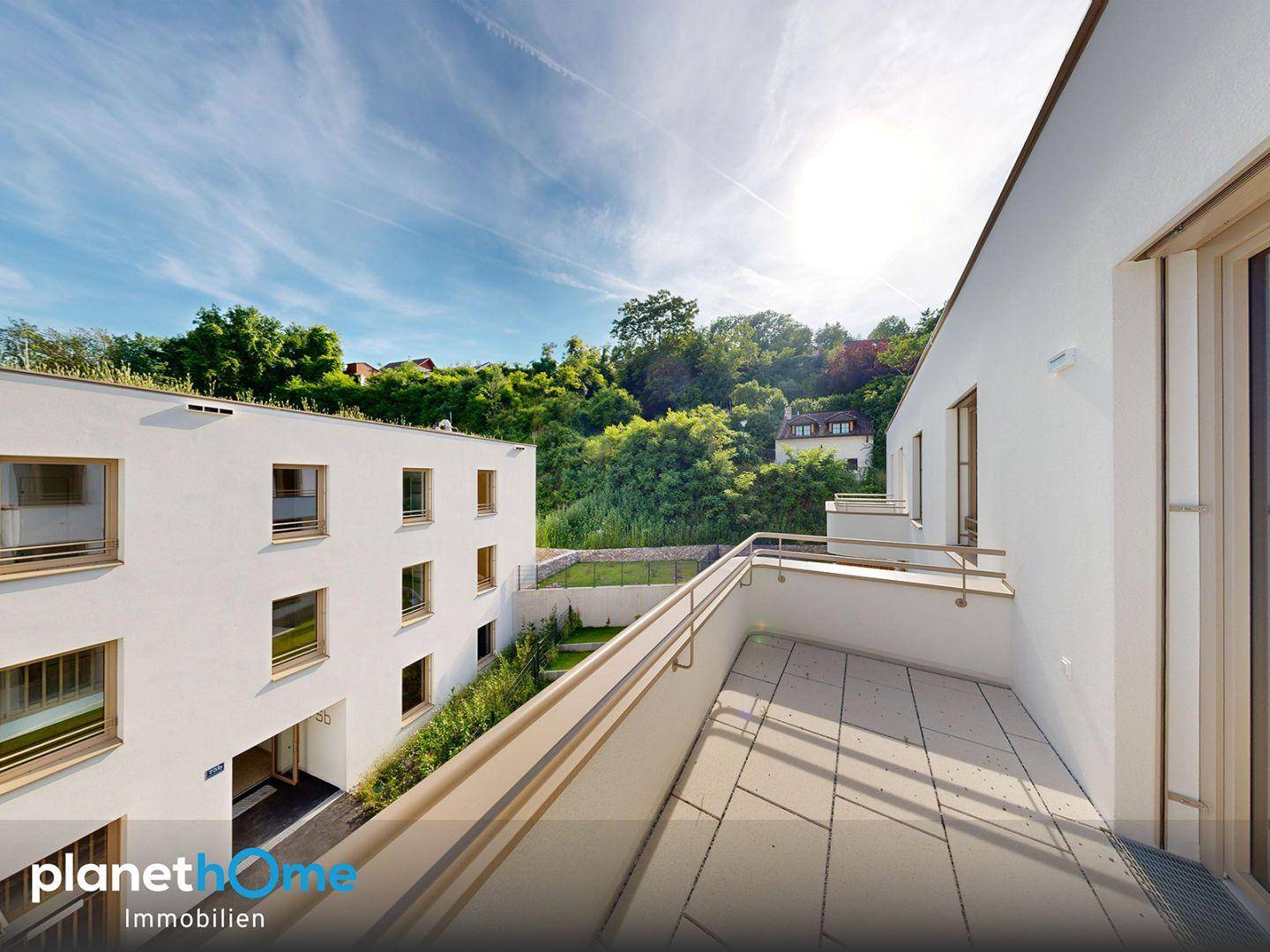 Geräumiger Balkon mit Fliesenboden und Blick auf die modernen Gebäude und grüne Umgebung.