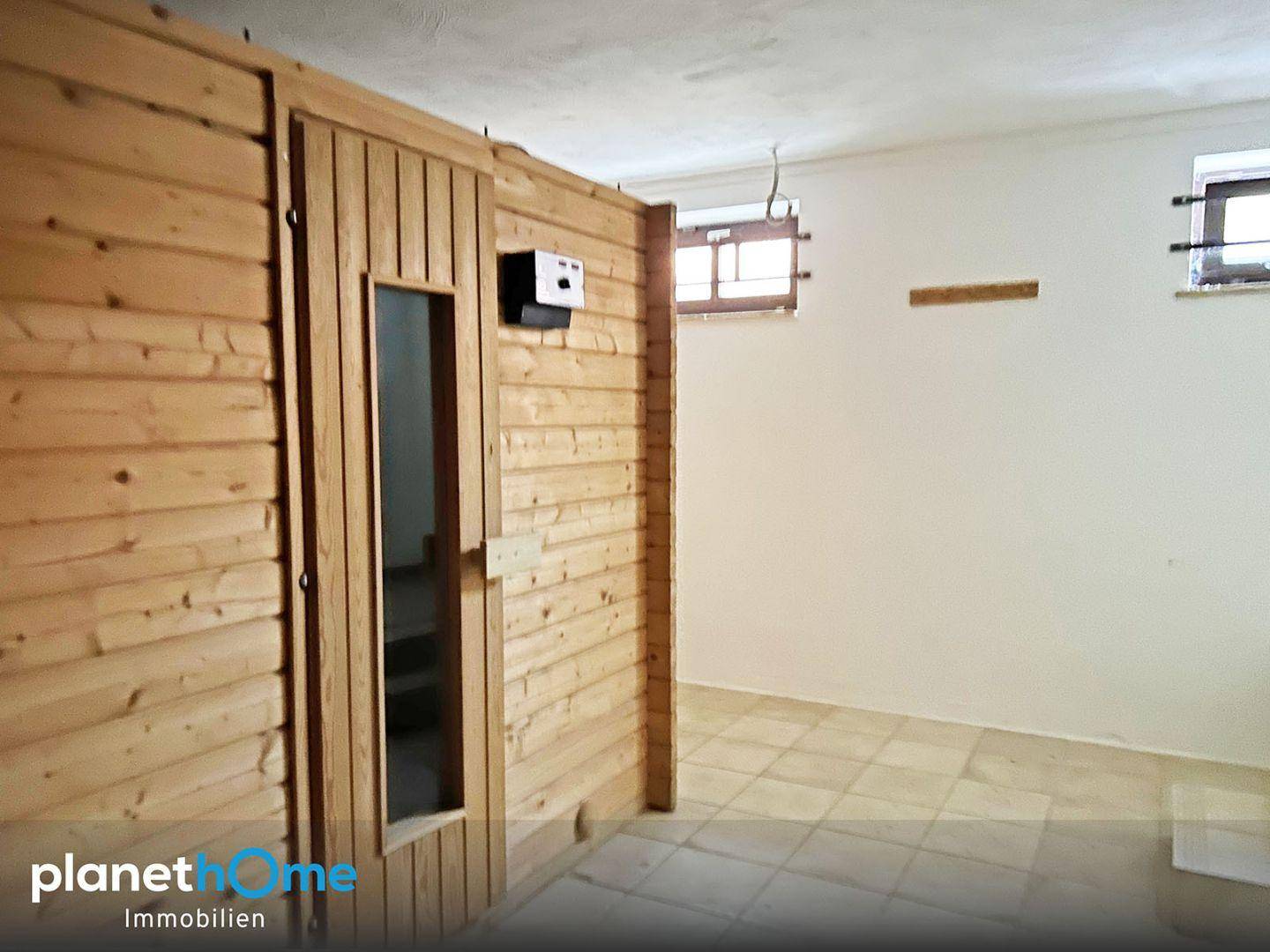 Kellerraum mit einer eingebauten Holzsauna und Fliesenboden.