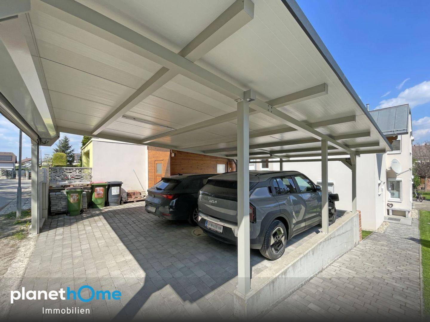 Geräumiger Carport mit Platz für zwei Fahrzeuge und gepflasterter Zufahrt.