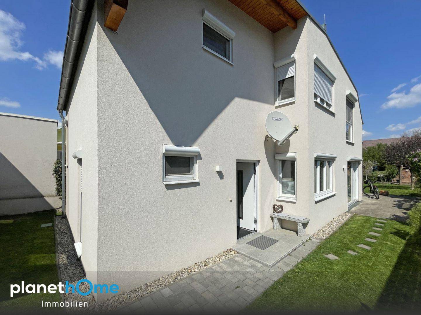 Seitliche Fassade des Hauses mit Eingangsbereich, Fenstern und Rollläden.