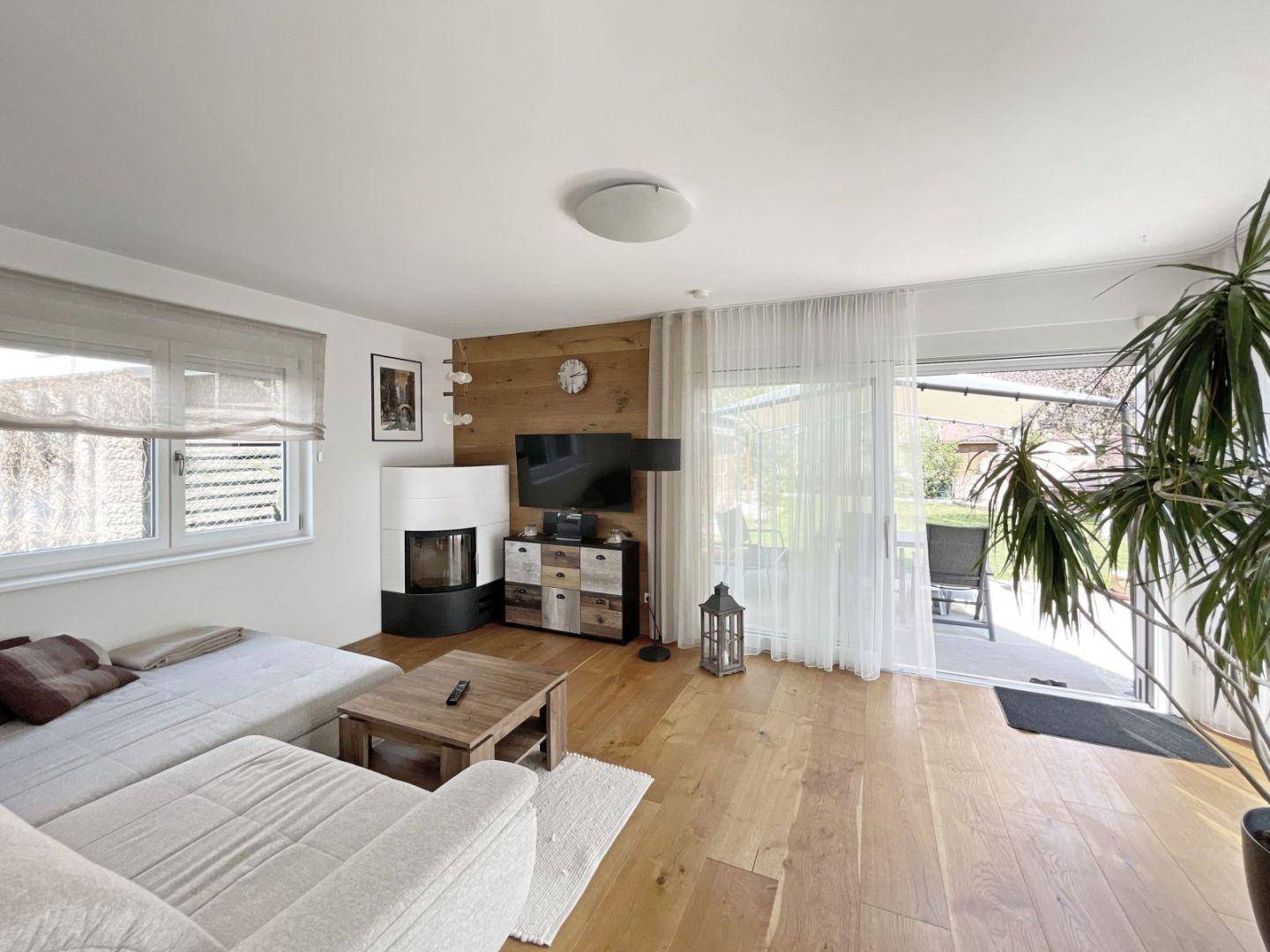 Helles Wohnzimmer mit Holzboden, Kaminofen und Zugang zur Terrasse.