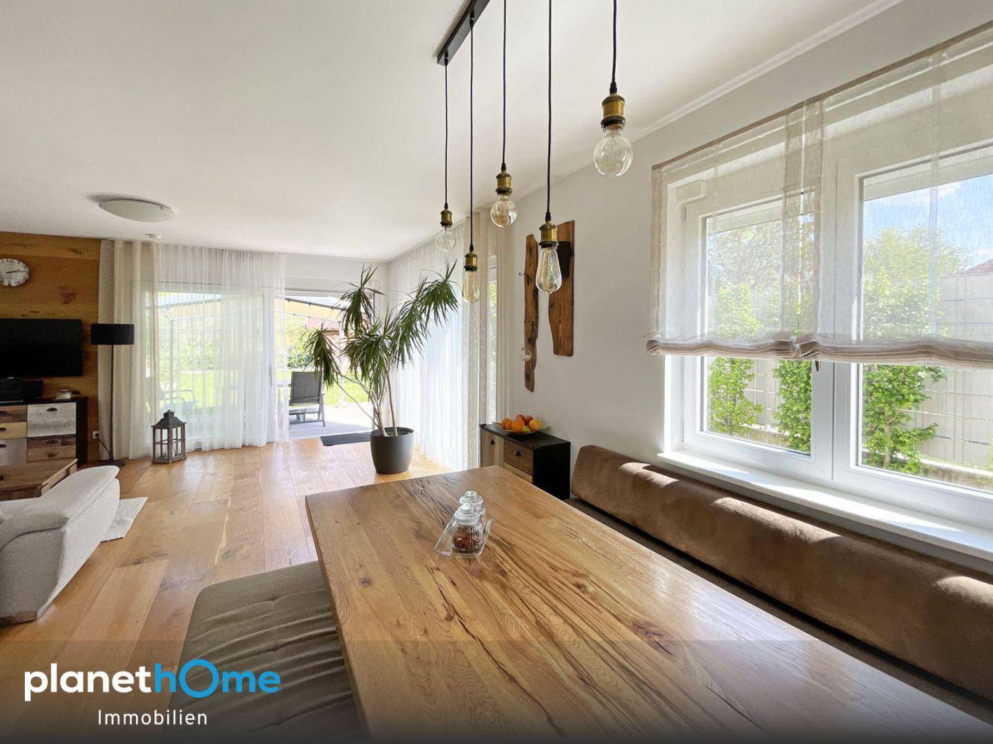 Essbereich mit großem Holztisch, Sitzbank und Blick in den Garten.