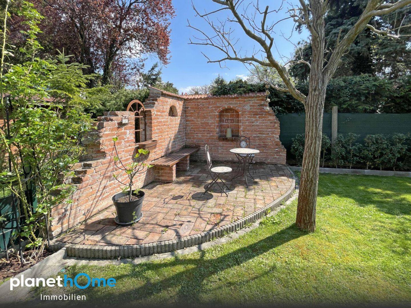 Gemütlicher Sitzbereich im Garten mit rustikalen Ziegelmauern und Gartenmöbeln.