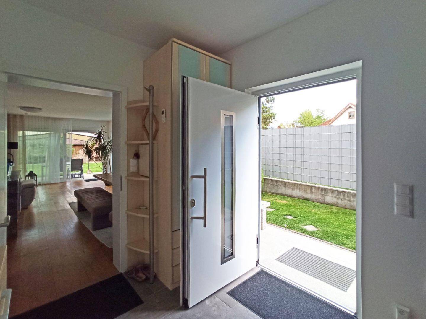 Heller Eingangsbereich mit Garderobe und Blick in den Wohnbereich und Garten.