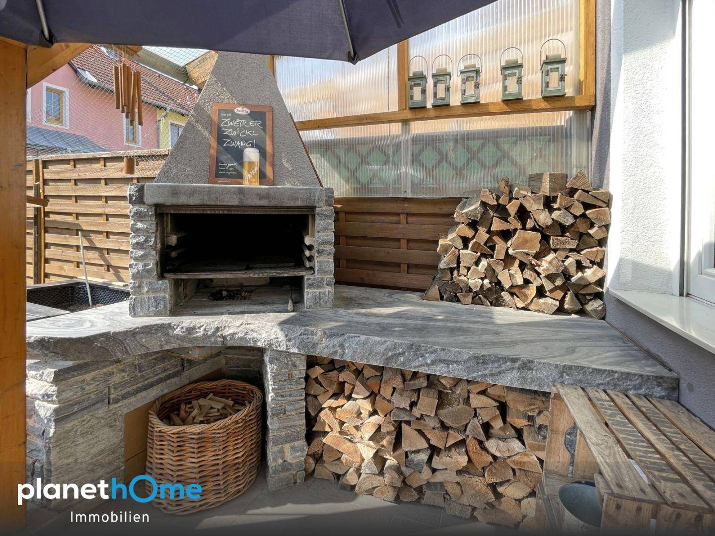 Detailansicht des gemauerten Grillbereichs mit integrierter Holzablage und rustikalem Charme auf der Terrasse.
