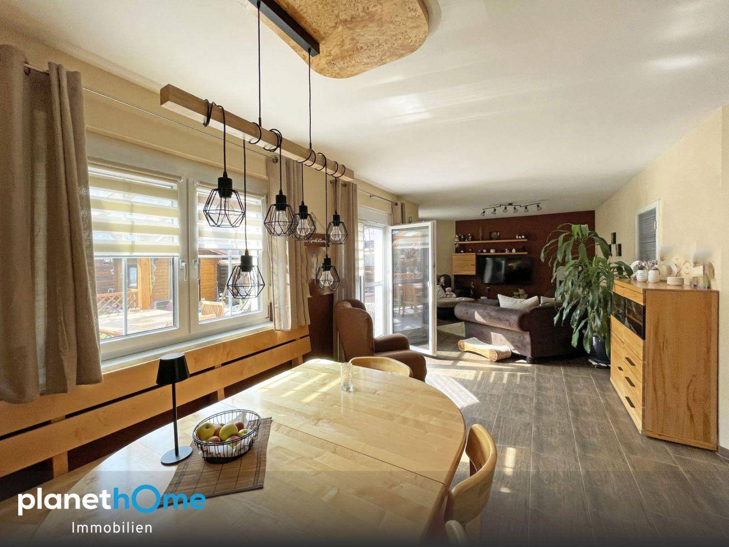 Heller Essbereich mit großem Holztisch und modernen Hängelampen, offen zum Wohnzimmer.