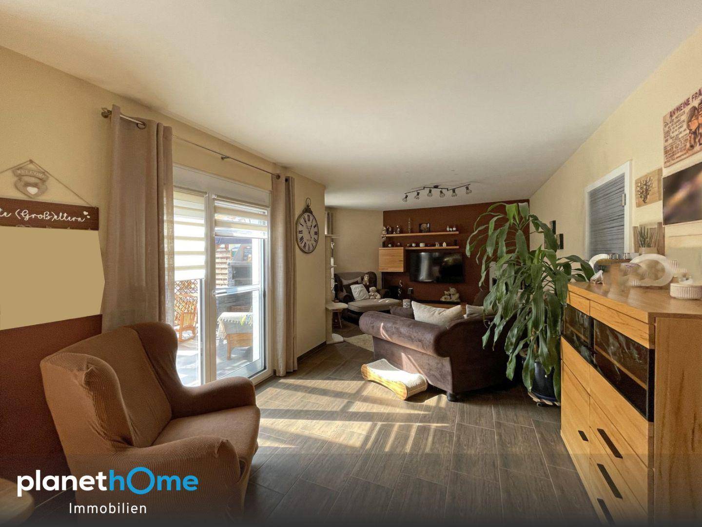 Wohnzimmer mit Fernsehecke, bequemen Sofas und Zugang zu einem Außenbereich, hell und einladend.