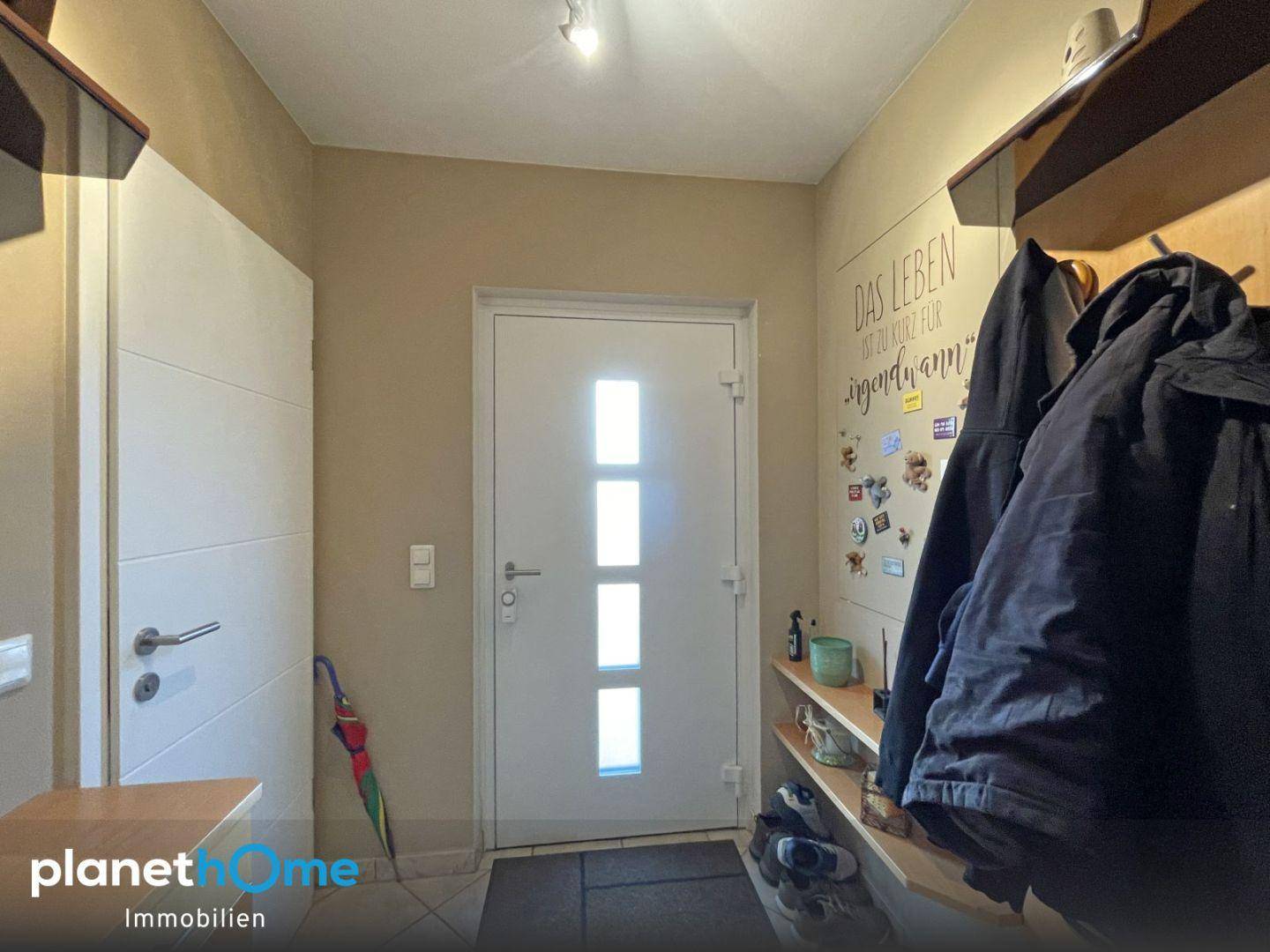 Heller Eingangsbereich mit Garderobe und moderner Haustür, einladend gestaltet.