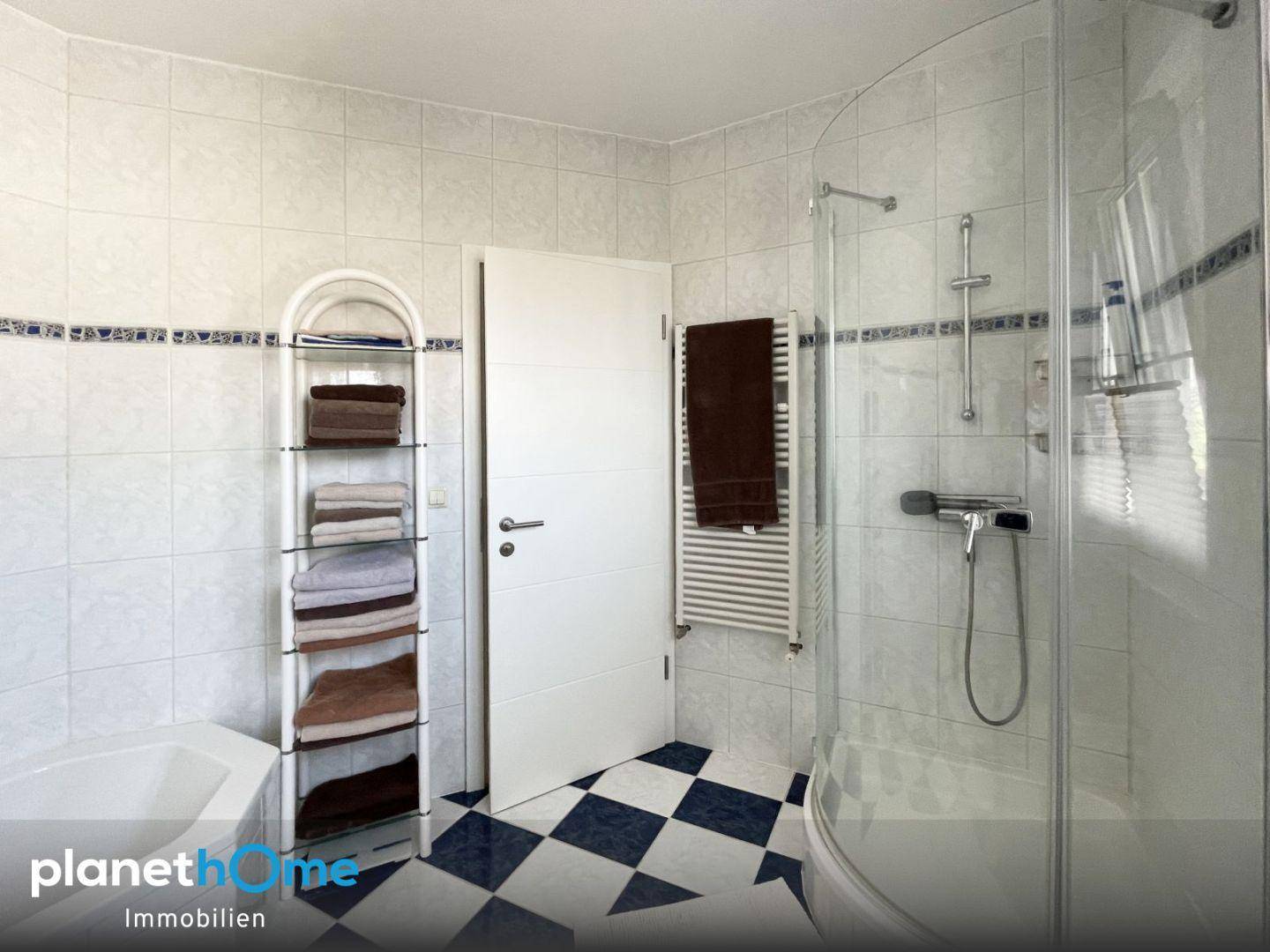 Badezimmer mit Duschkabine und beheiztem Handtuchhalter, praktisch und hell gefliest.