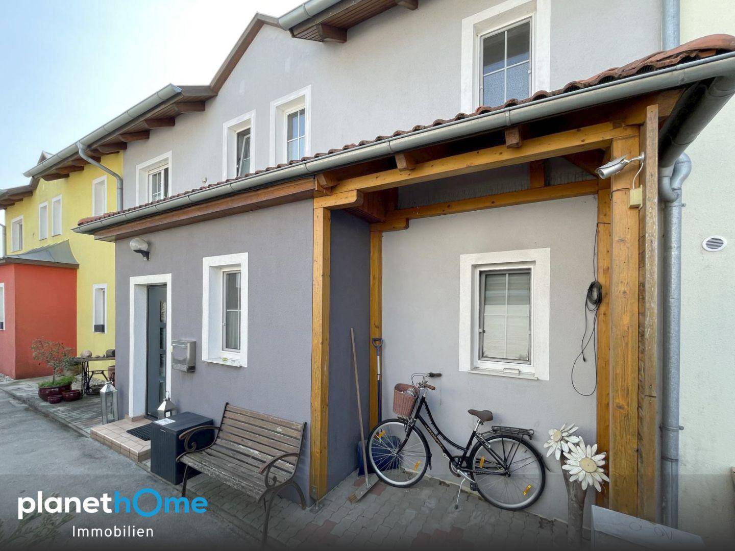 Hausfassade mit überdachtem Eingangsbereich und Abstellmöglichkeit für Fahrräder.