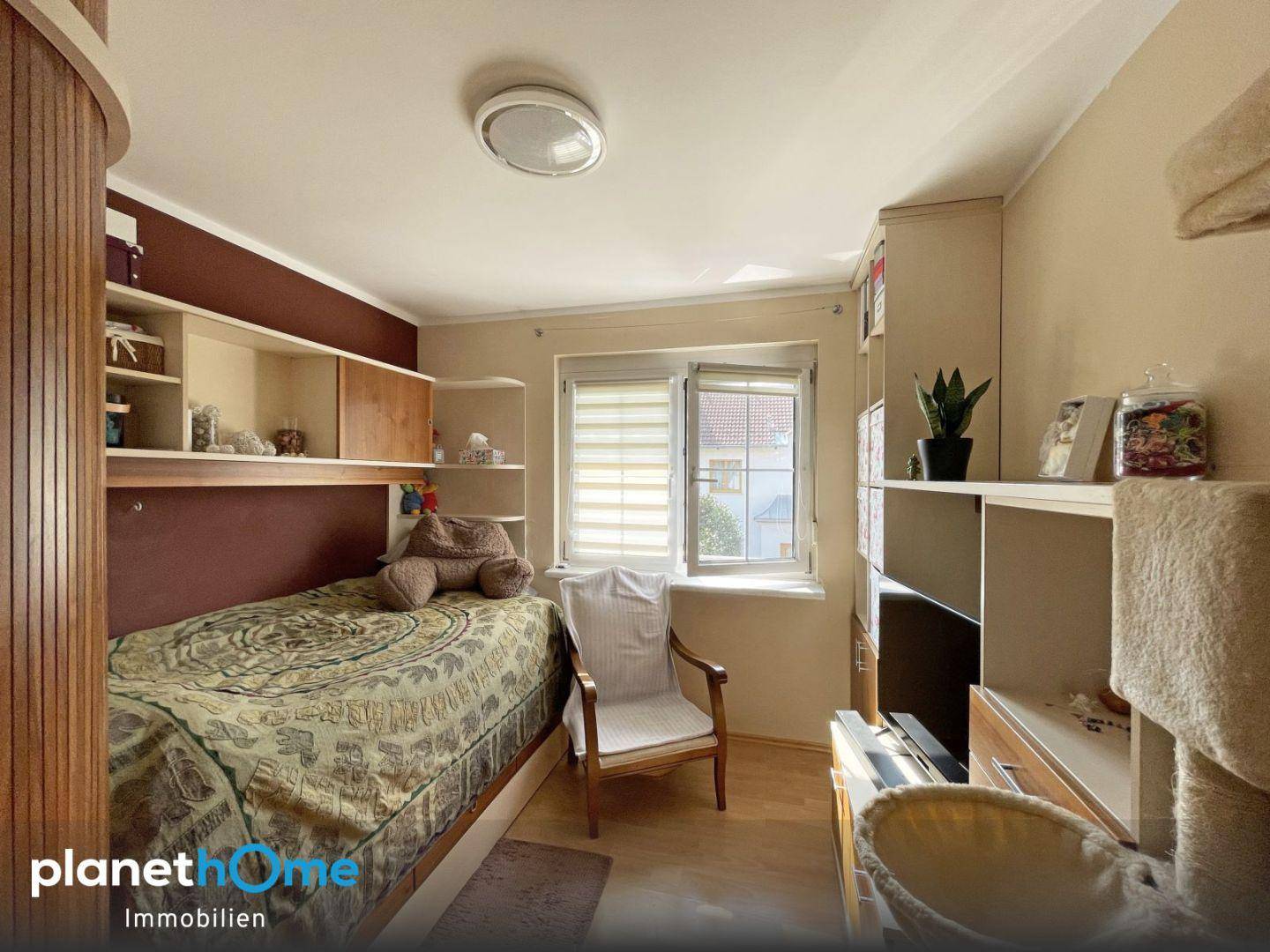 Helles Schlafzimmer mit Einzelbett und integrierten Regalen, ideal als Kinder- oder Arbeitszimmer.