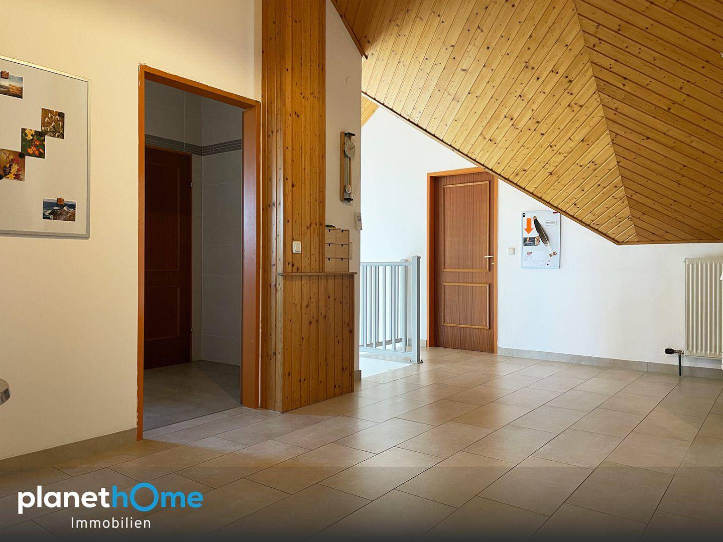 Flur mit Fliesenboden, Holzdecken und Zugang zu verschiedenen Räumen sowie einer Treppe.