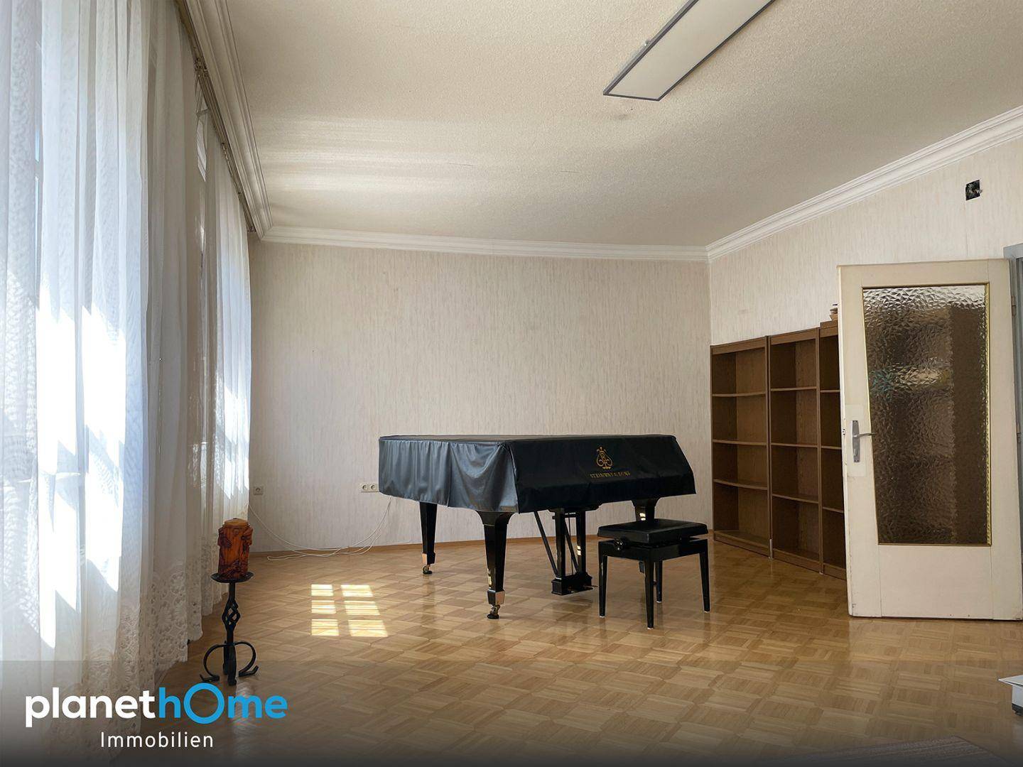 Großzügiges Wohnzimmer mit Parkettboden, hohen Decken und einem eleganten Flügel als Mittelpunkt.