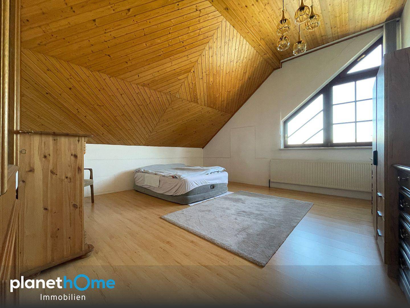 Schlafzimmer im Dachgeschoss mit Holzdecken, Dachschrägen und Holzboden, hell und geräumig.