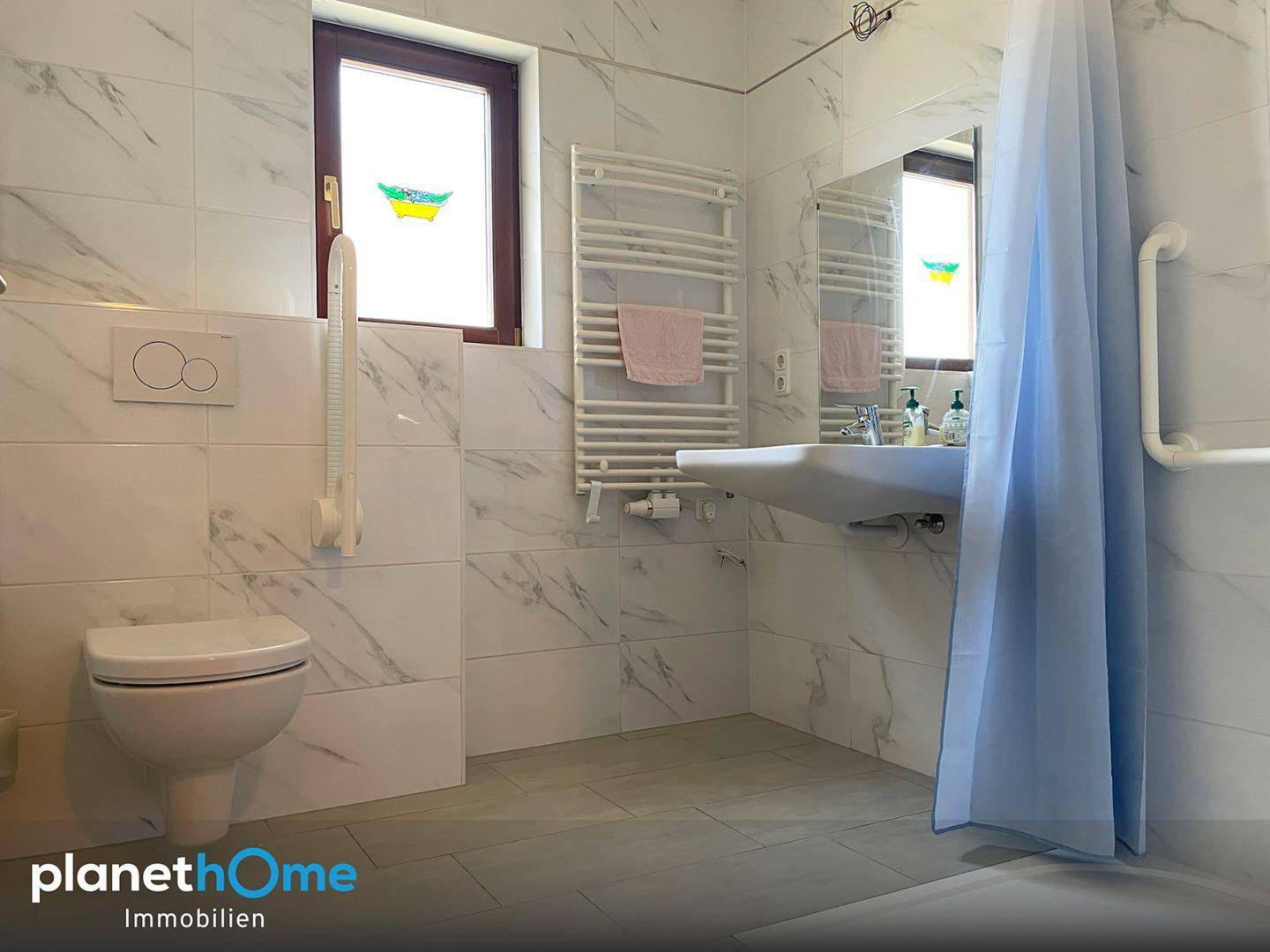 Modernes Badezimmer mit Wand-WC, Waschbecken, beheiztem Handtuchhalter und Haltegriffen für Komfort.