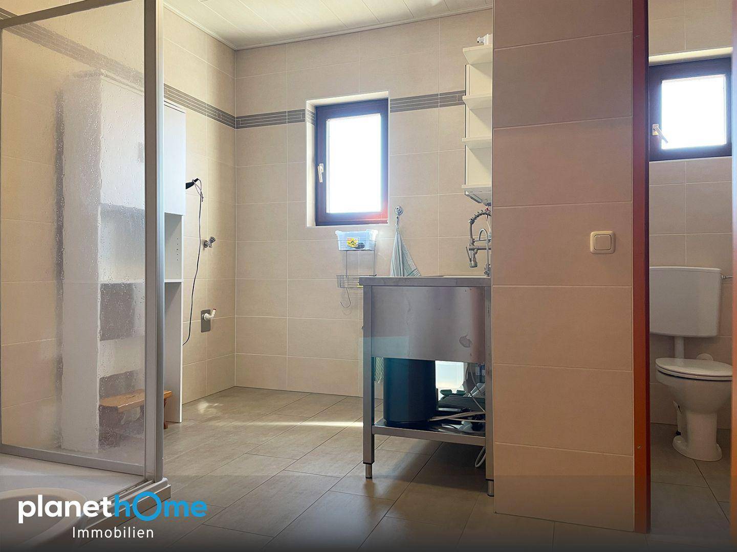 Badezimmer mit Duschkabine, WC und hellen Fliesen an Wänden und Boden in funktionalem Design.