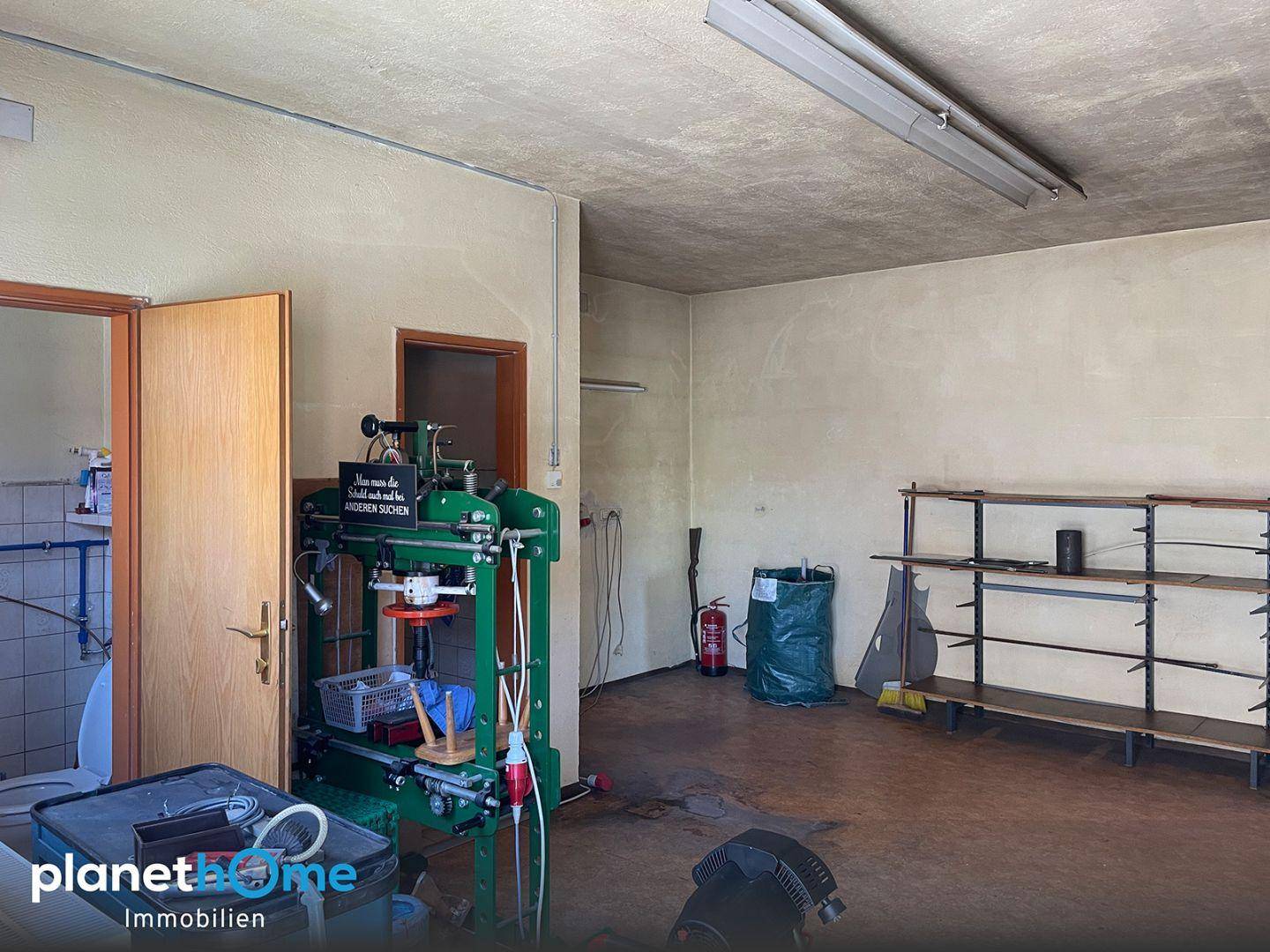 Werkstattraum mit Industrieboden, Maschinen und Regalen für Arbeitsmaterialien und Geräte.