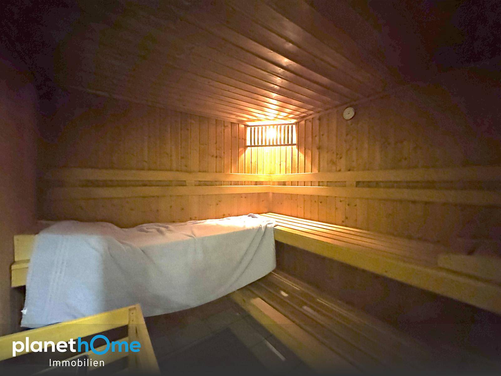Innenansicht einer traditionellen Holzsauna mit Bänken und gedämpfter Beleuchtung.