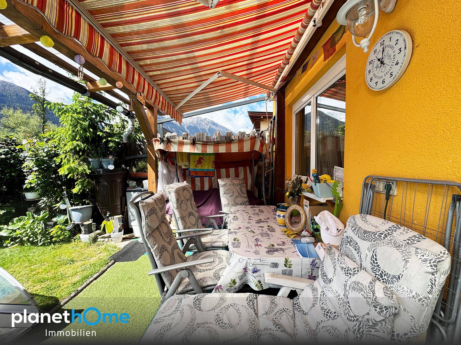Überdachte Terrasse mit Gartenmöbeln und Blick auf die Berge, ideal zum Entspannen.