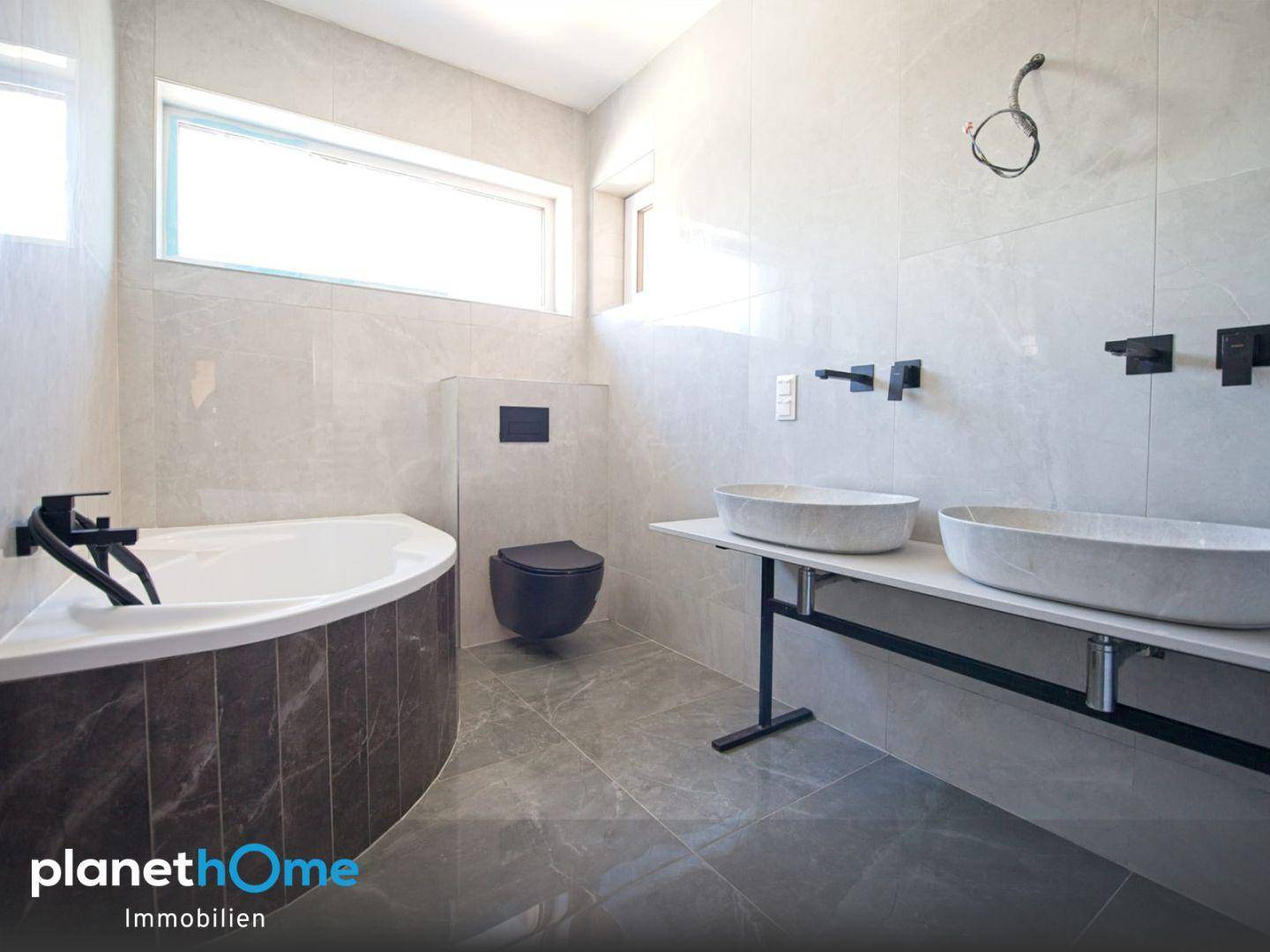 Modernes Badezimmer mit Eckbadewanne, Doppelwaschbecken und Wand-WC.