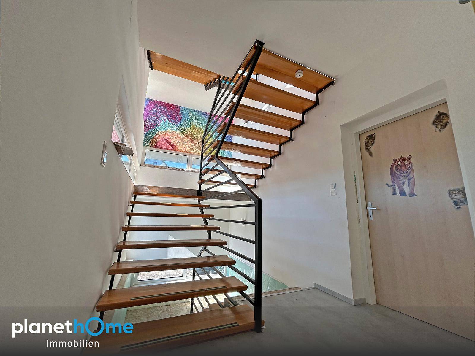 Moderne Holztreppe mit Metallgeländer und farbenfroher Wandgestaltung.