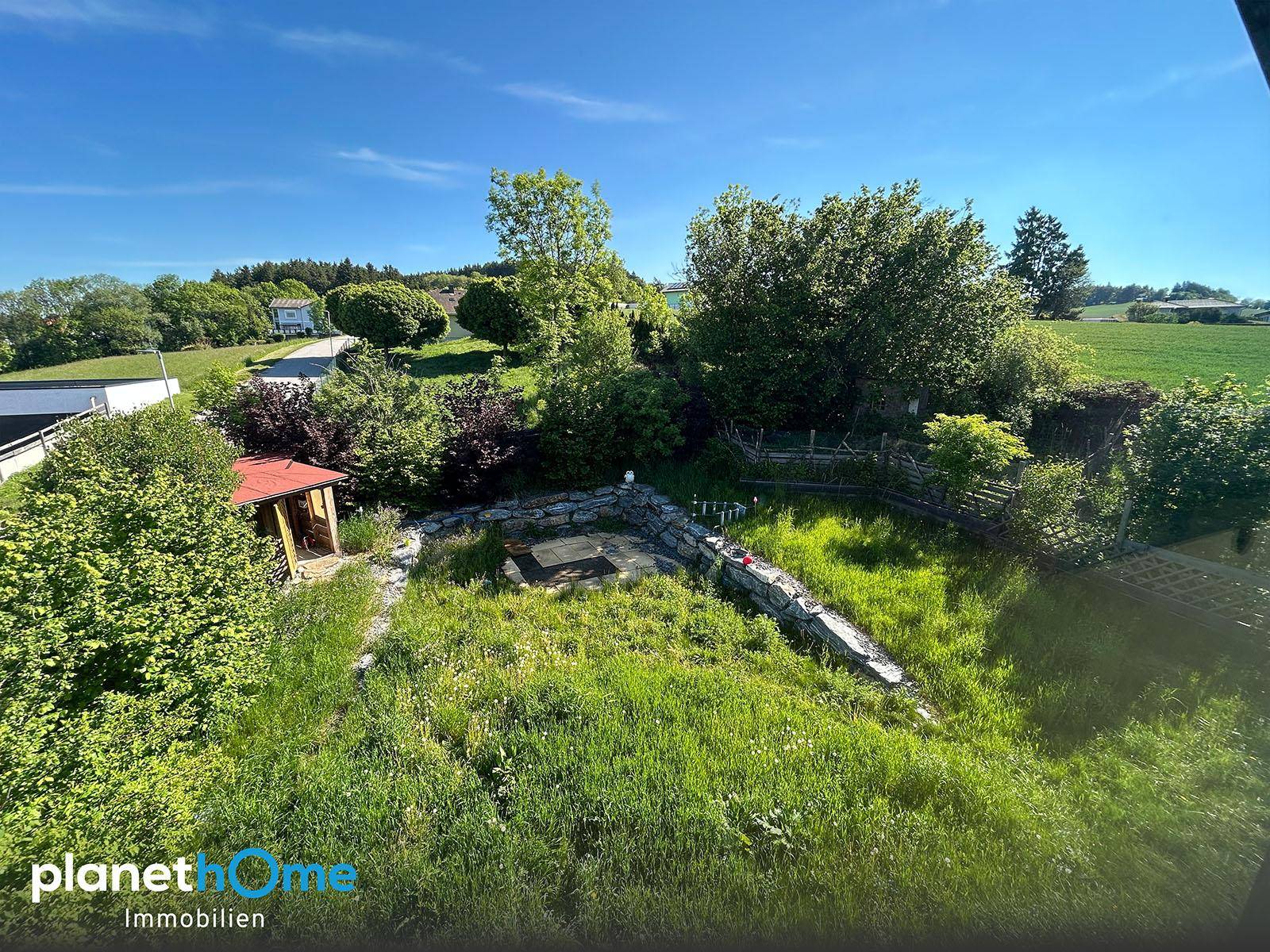 Weitläufiger Gartenbereich mit viel Grün, einem Gartenhaus und ländlichem Ausblick.