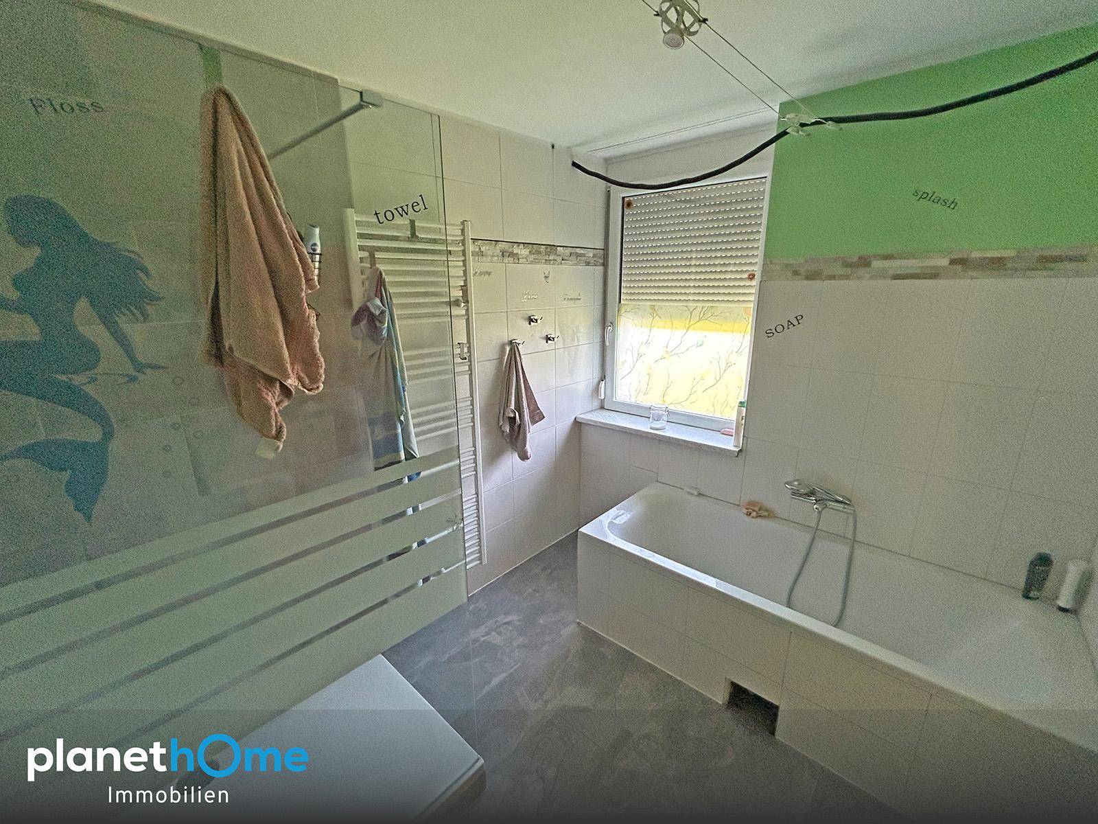 Badezimmer mit Badewanne, Fliesen und beheiztem Handtuchhalter.