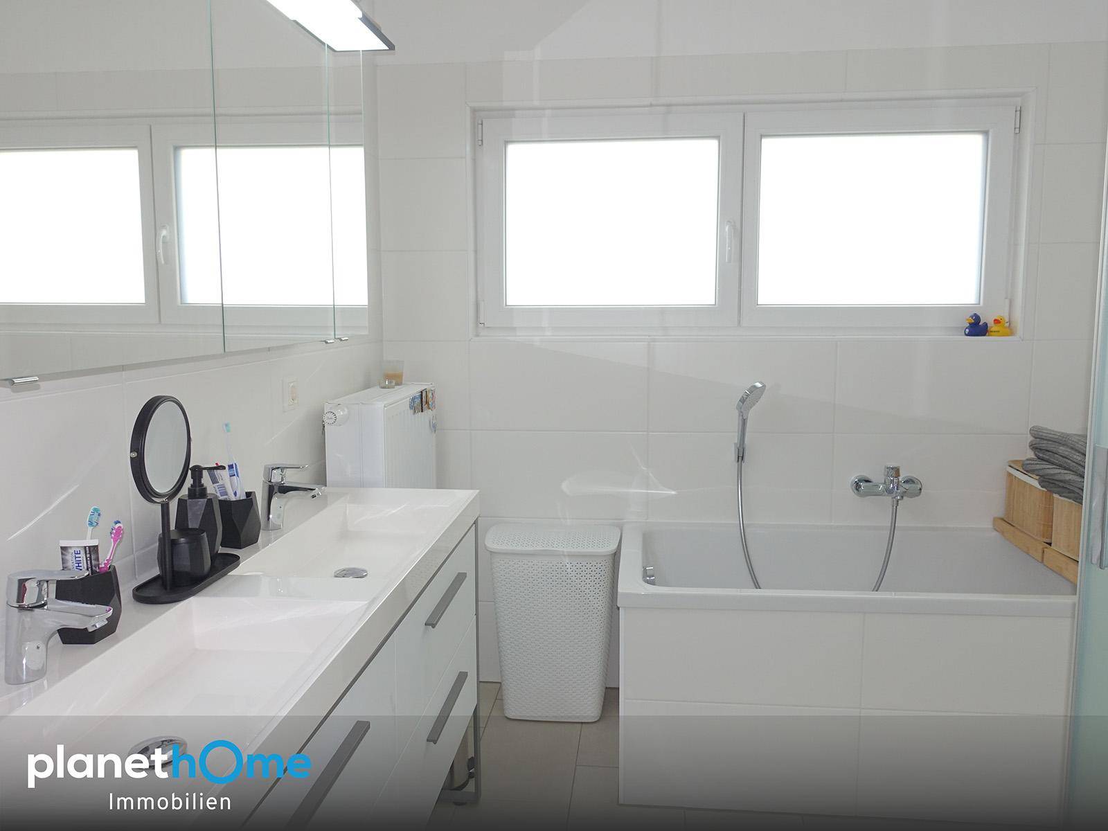 Modernes Badezimmer mit Doppelwaschbecken, Badewanne und einem großen Fenster für Tageslicht.