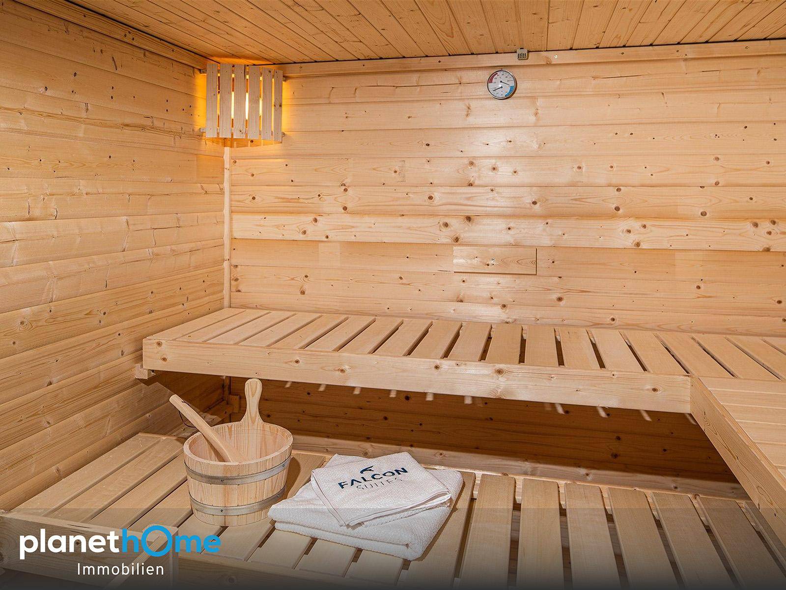 Traditionelle Holzsauna mit Sitzbänken und klassischem Zubehör, bereit zur Entspannung.