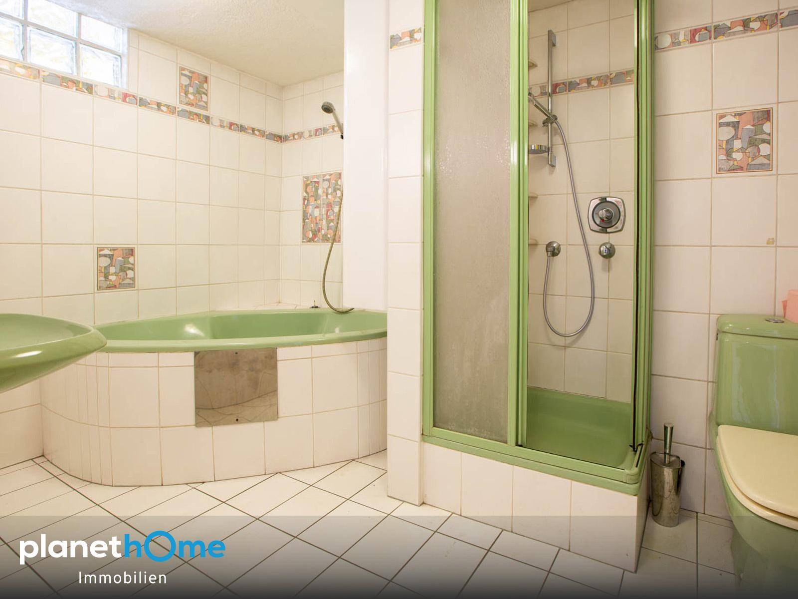 Badezimmer im Stil der 80er Jahre mit grüner Badewanne, Duschkabine und Fliesen.