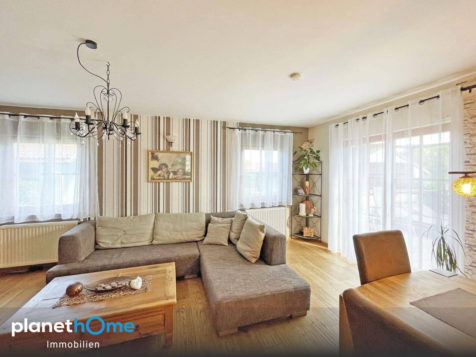 Gemütliches Wohnzimmer mit großem Ecksofa, Holzboden und gestreiften Tapeten.