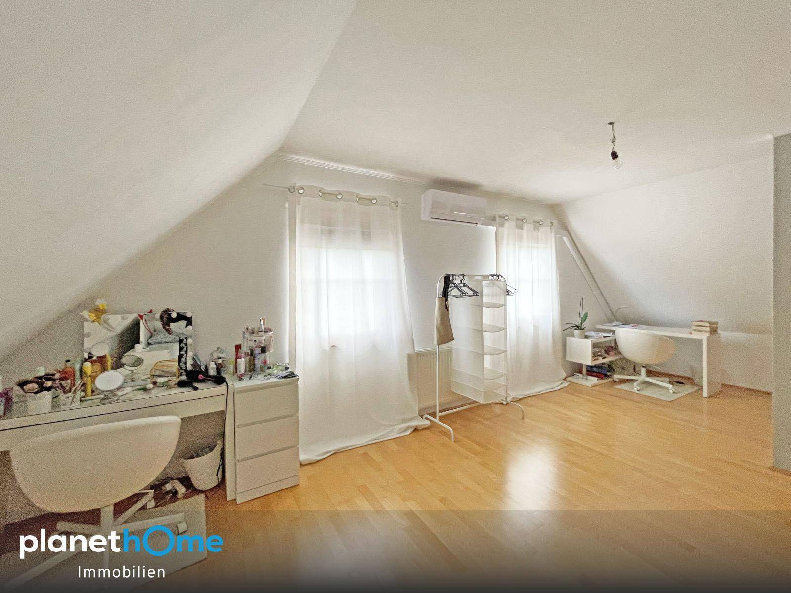 Geräumiges Zimmer im Dachgeschoss mit Holzboden, Schminktisch und Klimaanlage.