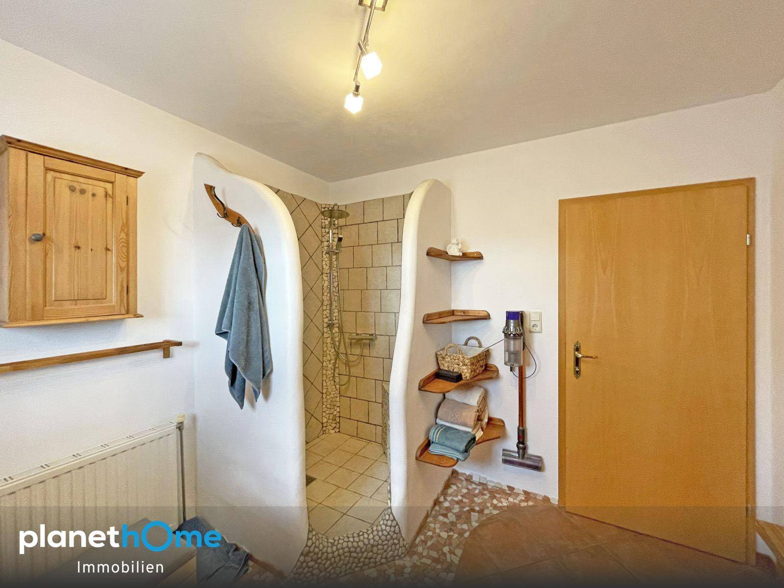 Badezimmer mit begehbarer Dusche, gefliestem Boden und rustikalem Holzschrank.
