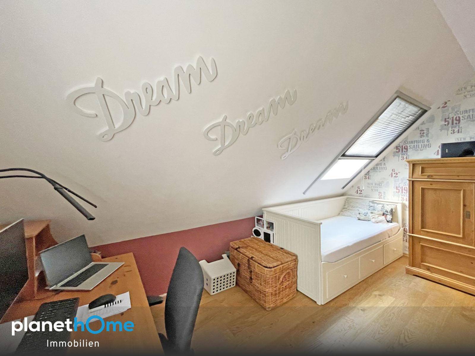 Gemütliches Zimmer im Dachgeschoss mit Schreibtisch, Bett und Dachfenster.