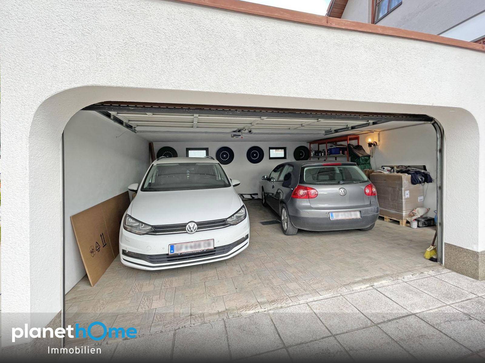 Geräumige Doppelgarage mit zwei geparkten Autos und Stauraum.