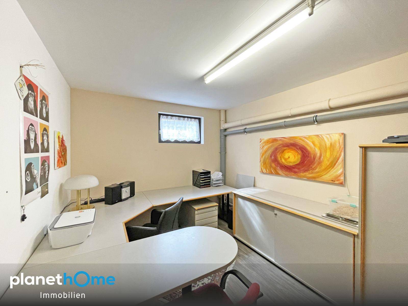 Funktionales Büro im Kellergeschoss mit großem Schreibtisch und kleinem Fenster.