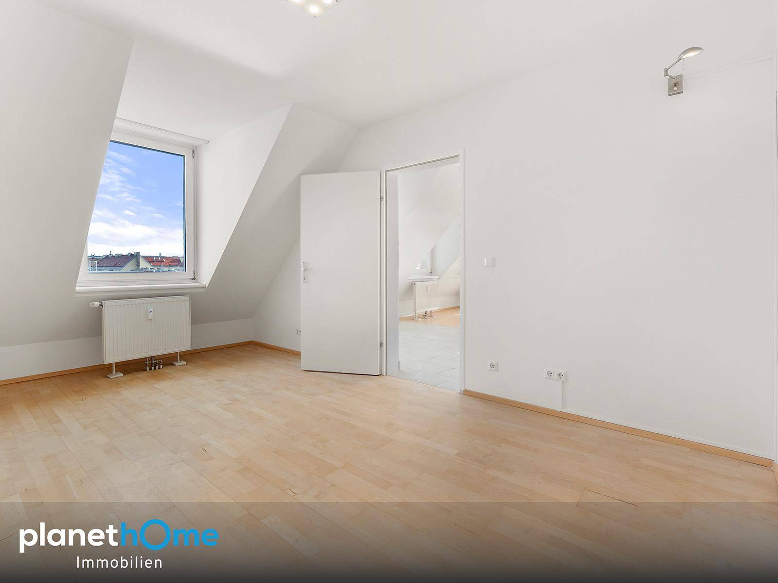 Heller Raum mit Holzboden, Dachschräge und Fenster, bietet vielseitige Nutzungsmöglichkeiten.