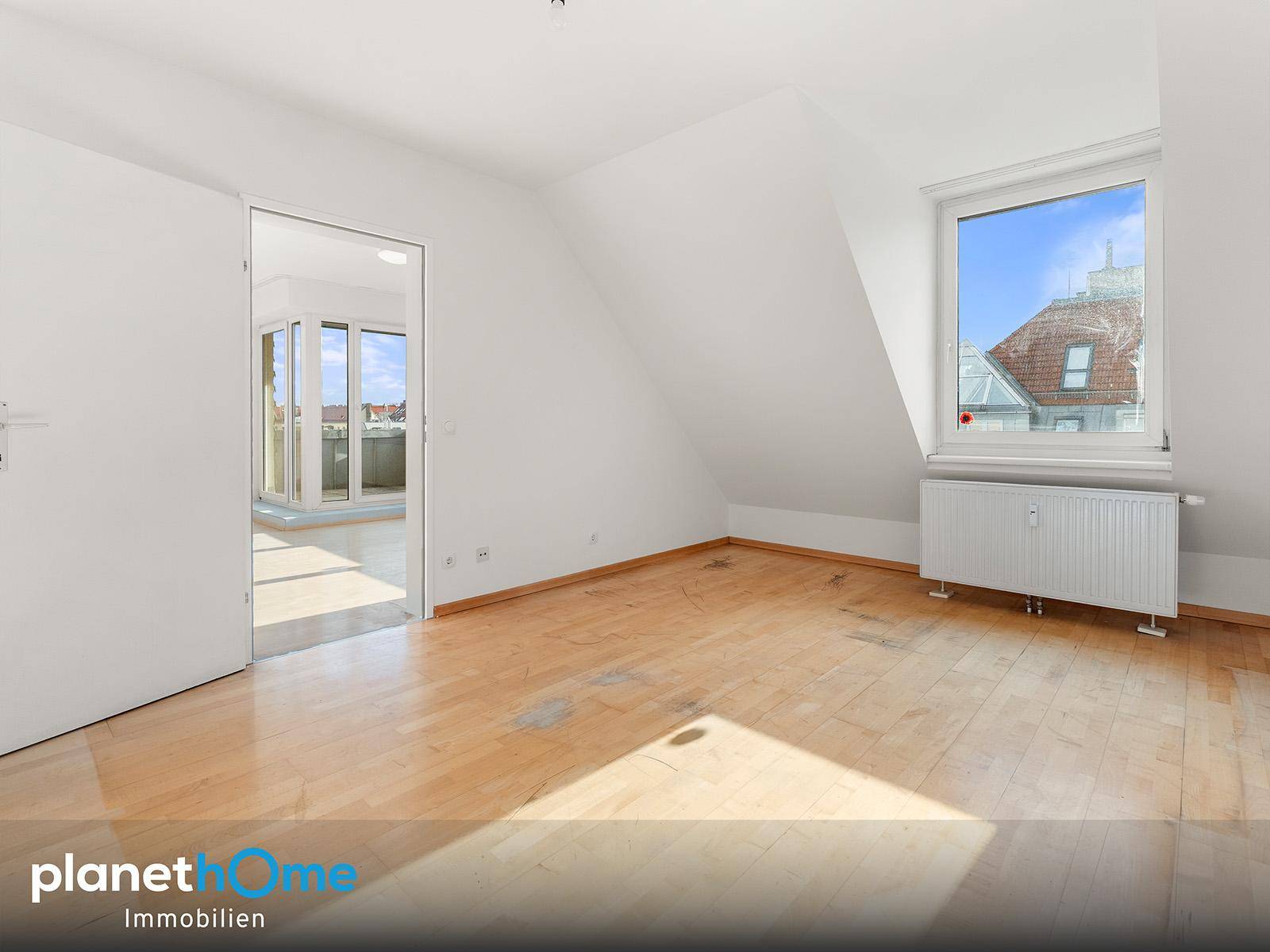Heller Raum mit Holzboden, Dachschräge und Fenster, ideal als Schlaf- oder Arbeitszimmer.