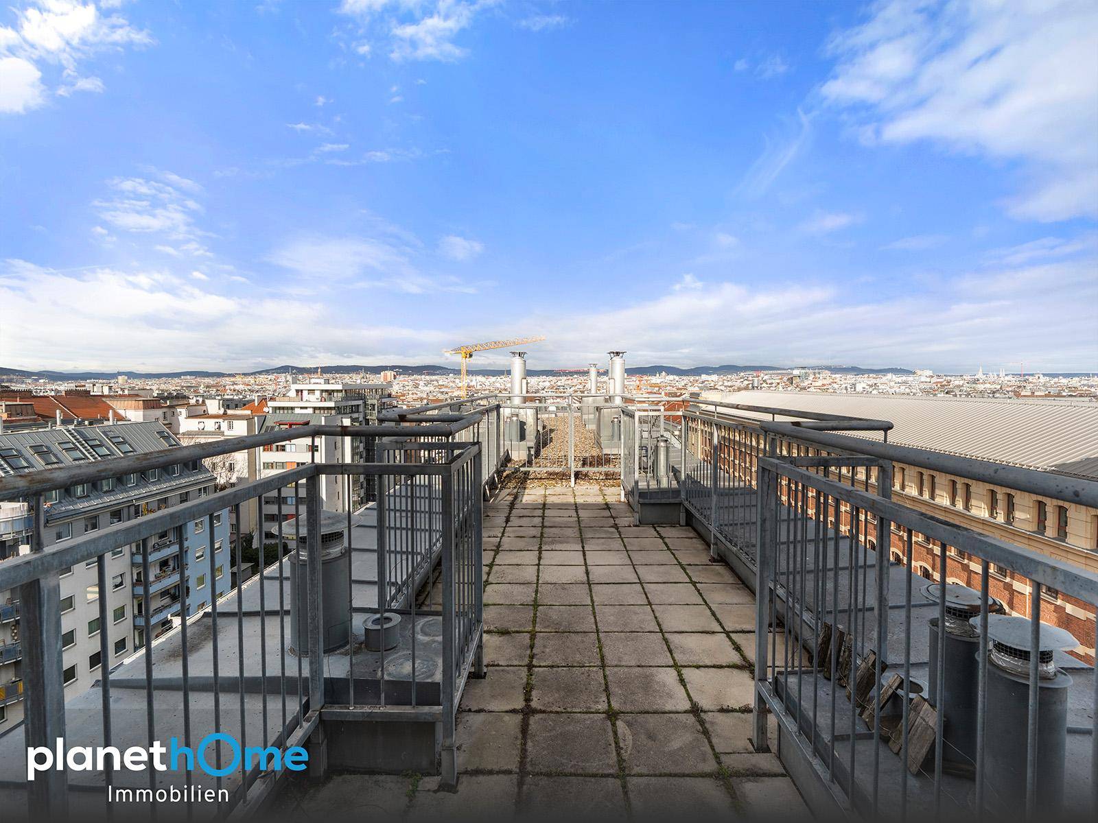 Weitläufige Dachterrasse mit Fliesenboden und Panoramablick über die Stadt.