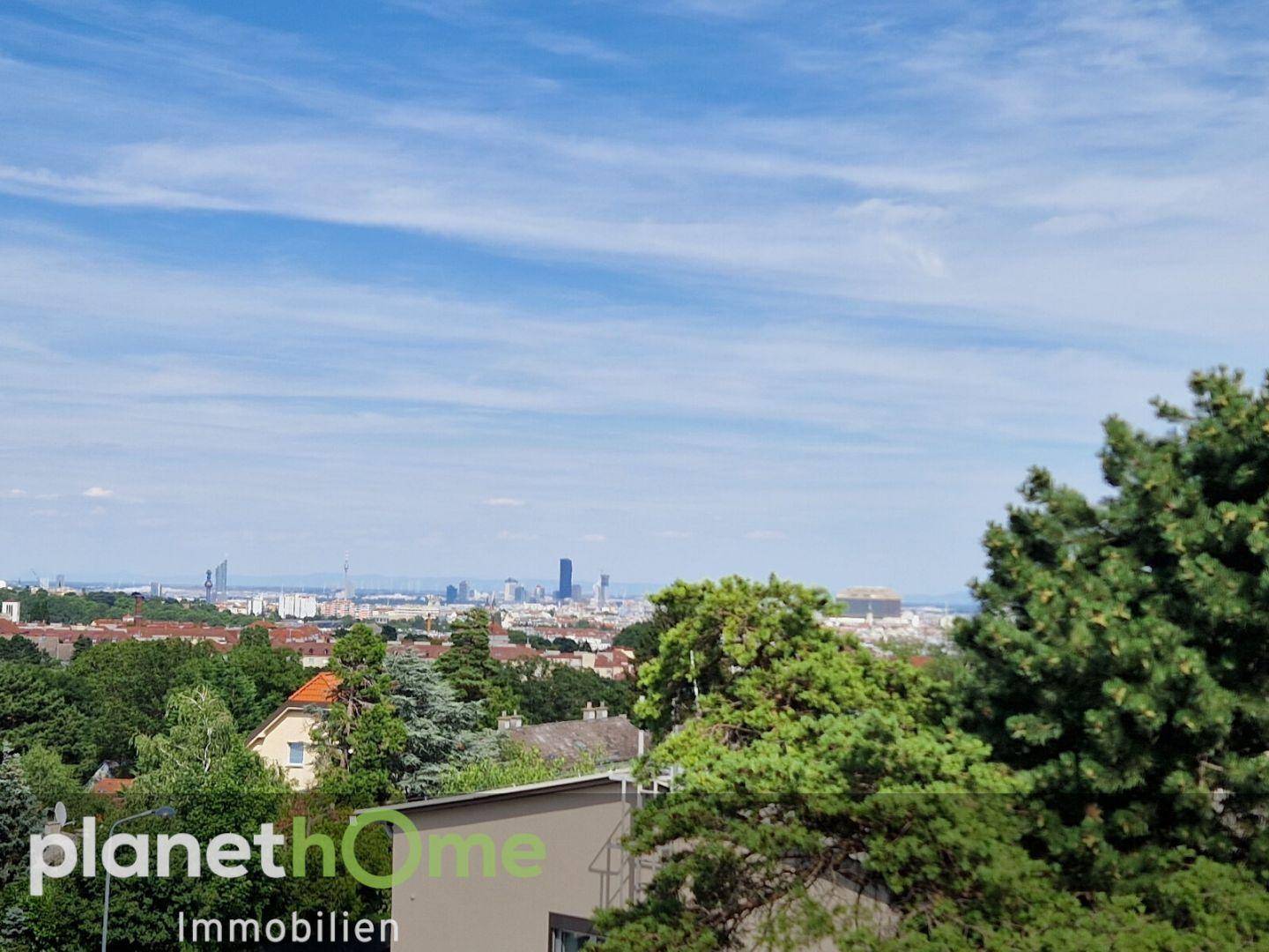 Weitläufiger Panoramablick über die Stadt und die grüne Landschaft unter blauem Himmel.
