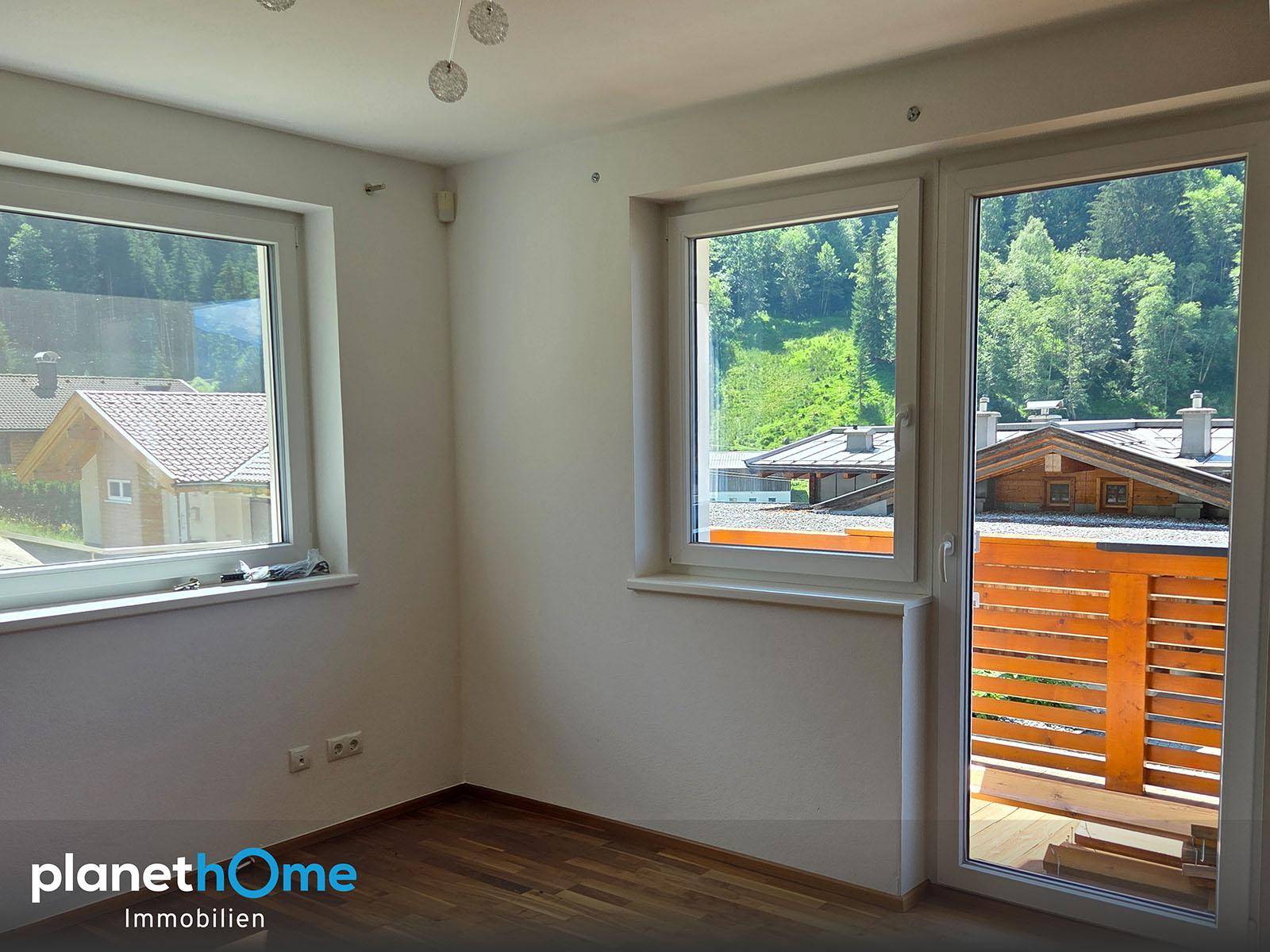 Heller Raum mit Holzboden und Zugang zu einem Balkon, bietet viel natürliches Licht.