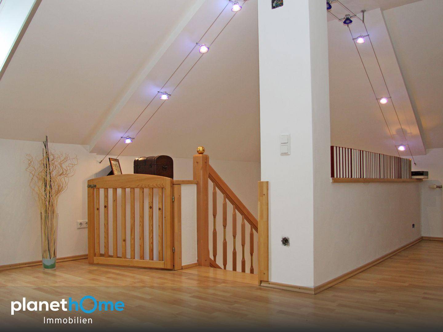 Heller Dachbodenbereich mit Holztreppe und schrägen Decken, ideal für zusätzlichen Wohnraum.