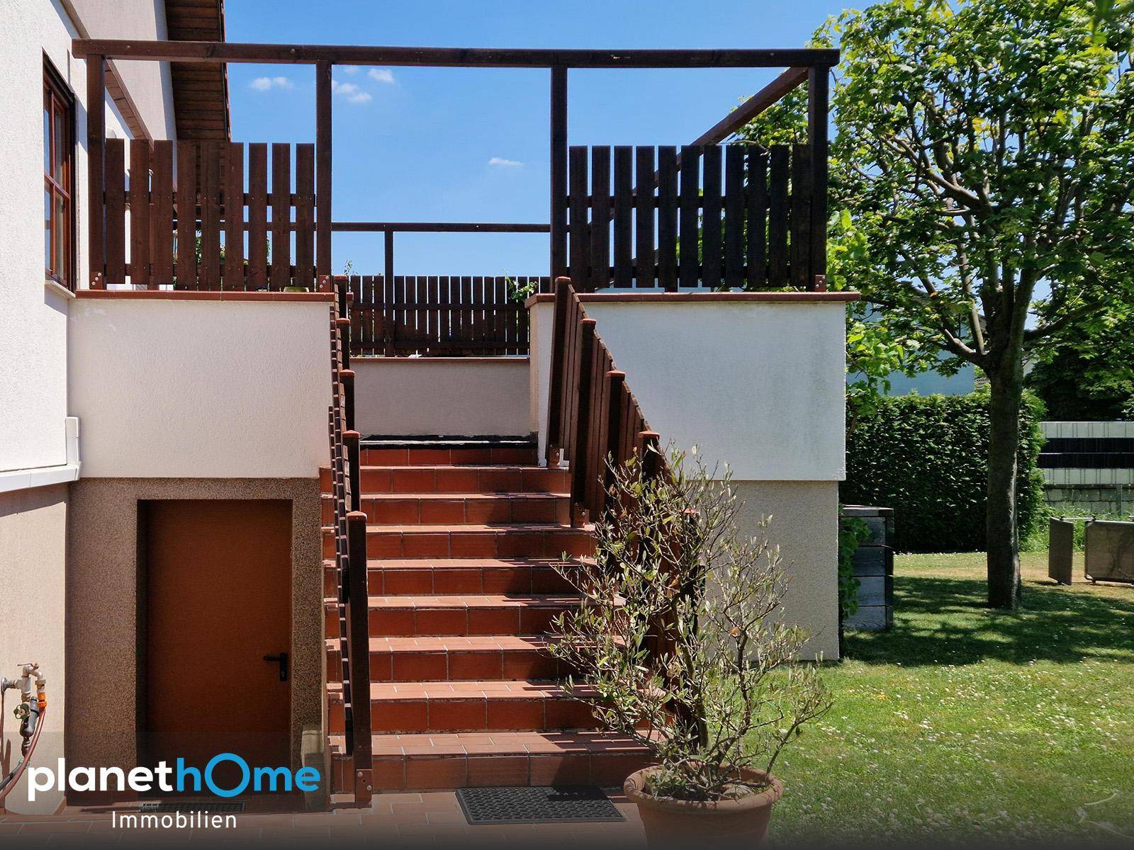 Detailansicht der Holztreppe, die zur erhöhten Terrasse und dem Garten führt.