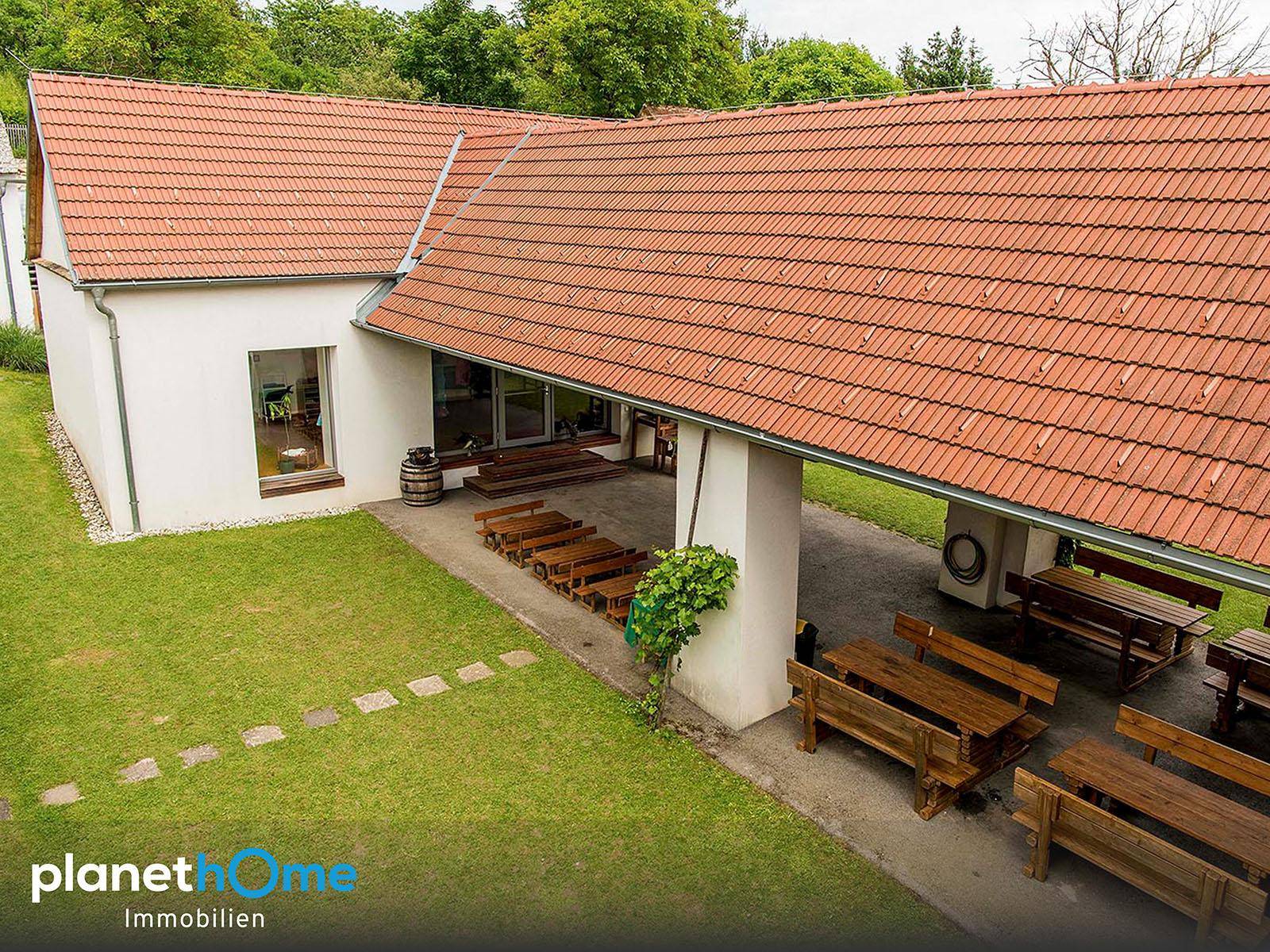 Gepflegter Gartenbereich mit Rasen und einer überdachten Terrasse, umgeben von ländlicher Idylle.