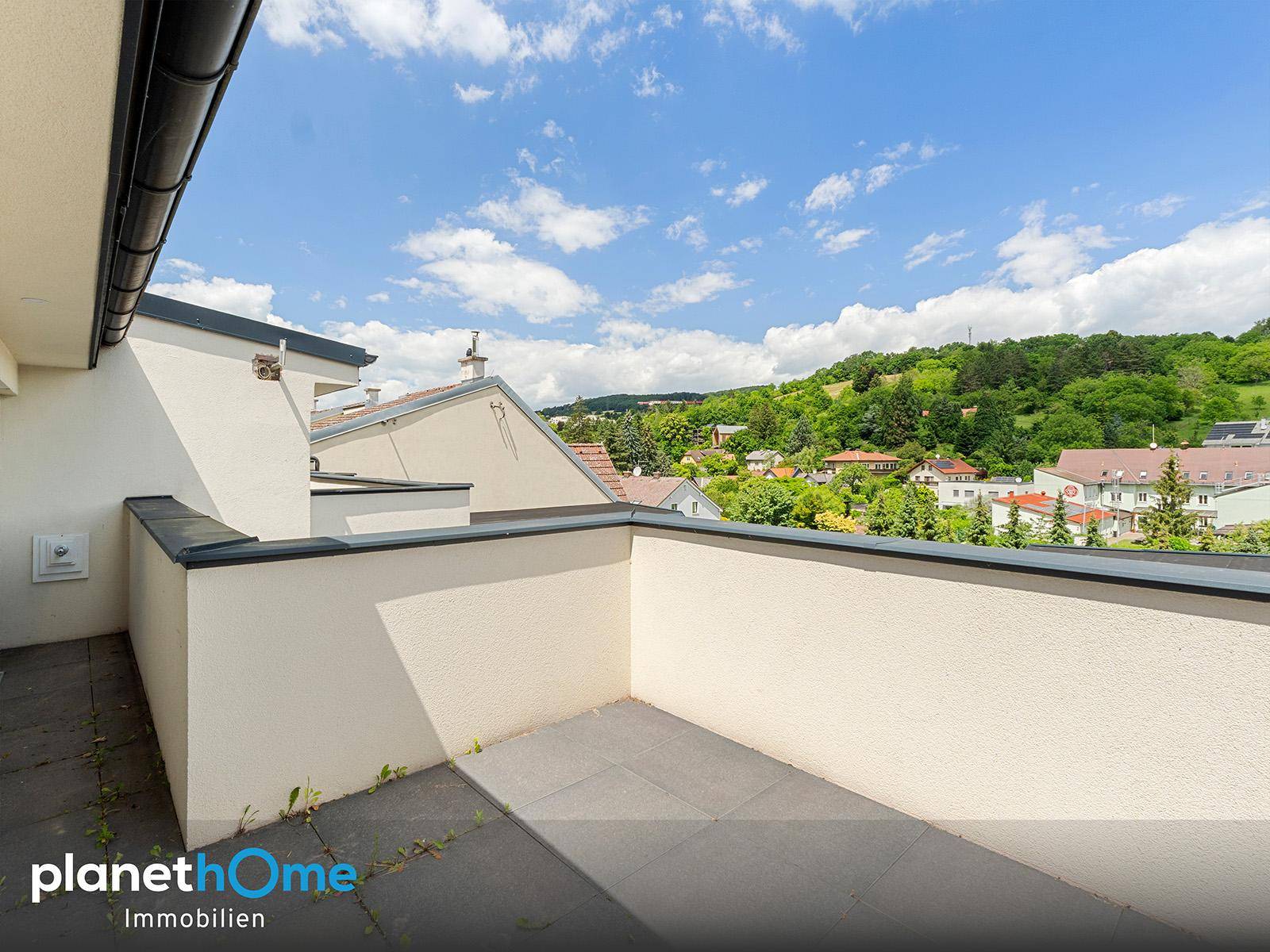 Weiterer Blick auf den leeren Balkon mit Fliesenboden und die umliegende grüne Hügellandschaft.